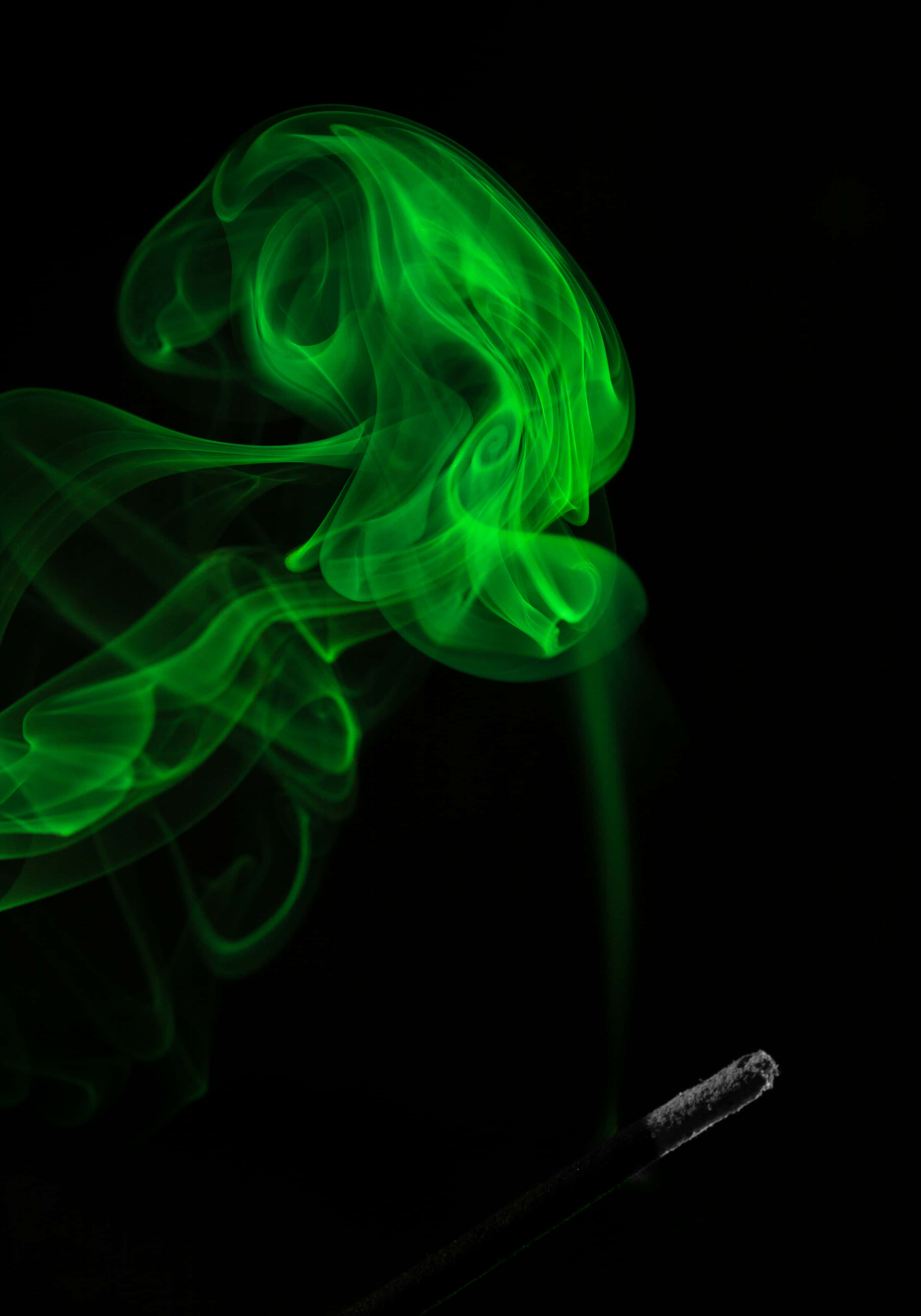 Green Smoke 桌布 壁紙 — 鮮豔的綠色煙霧在純黑色背景上優雅地盤旋，從深色香棒中升起。
