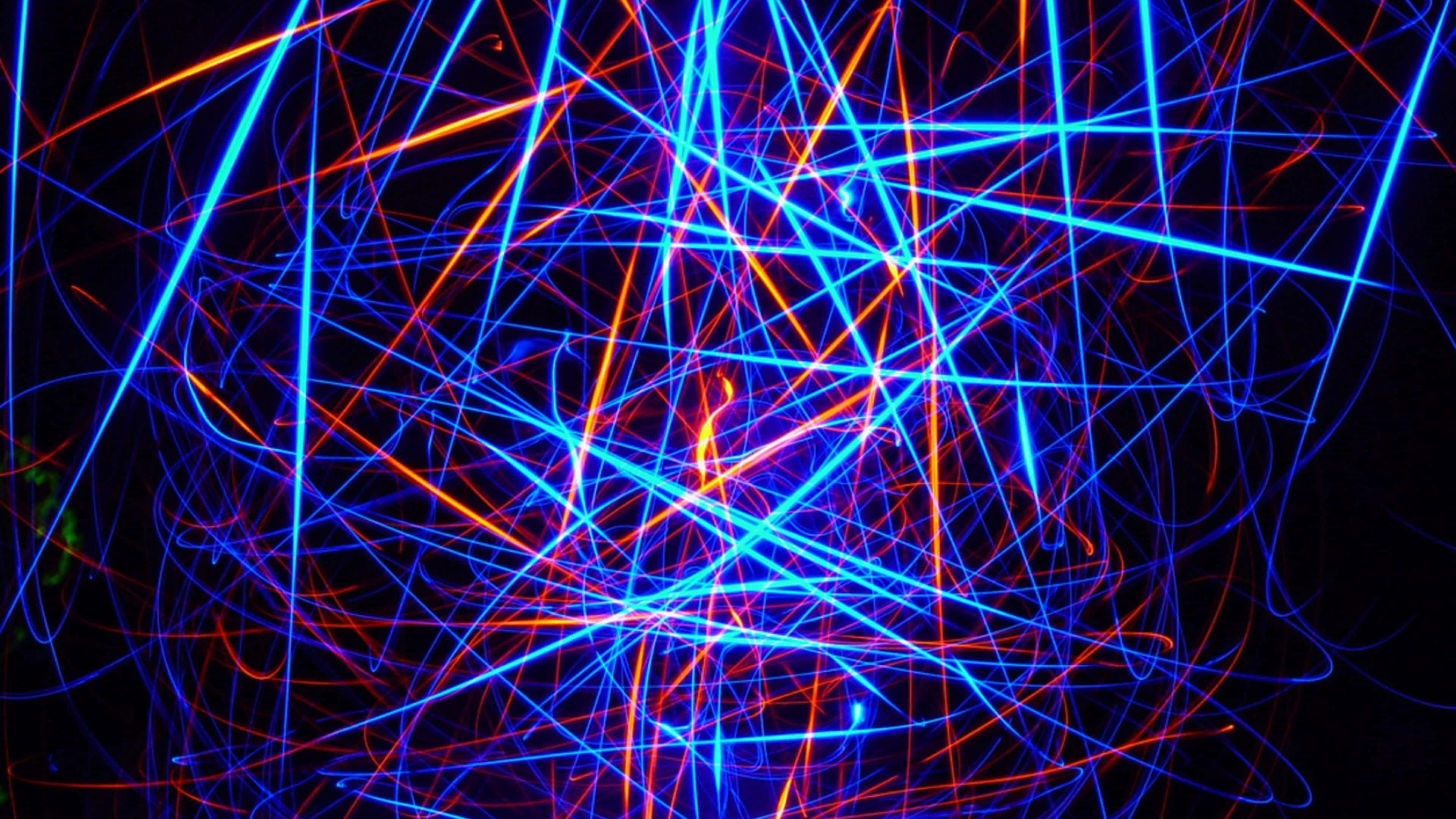 Neon Lights 桌布 壁紙 — 鮮豔的藍色和橙色光軌在黑色背景上交錯，形成混亂的抽象圖案。