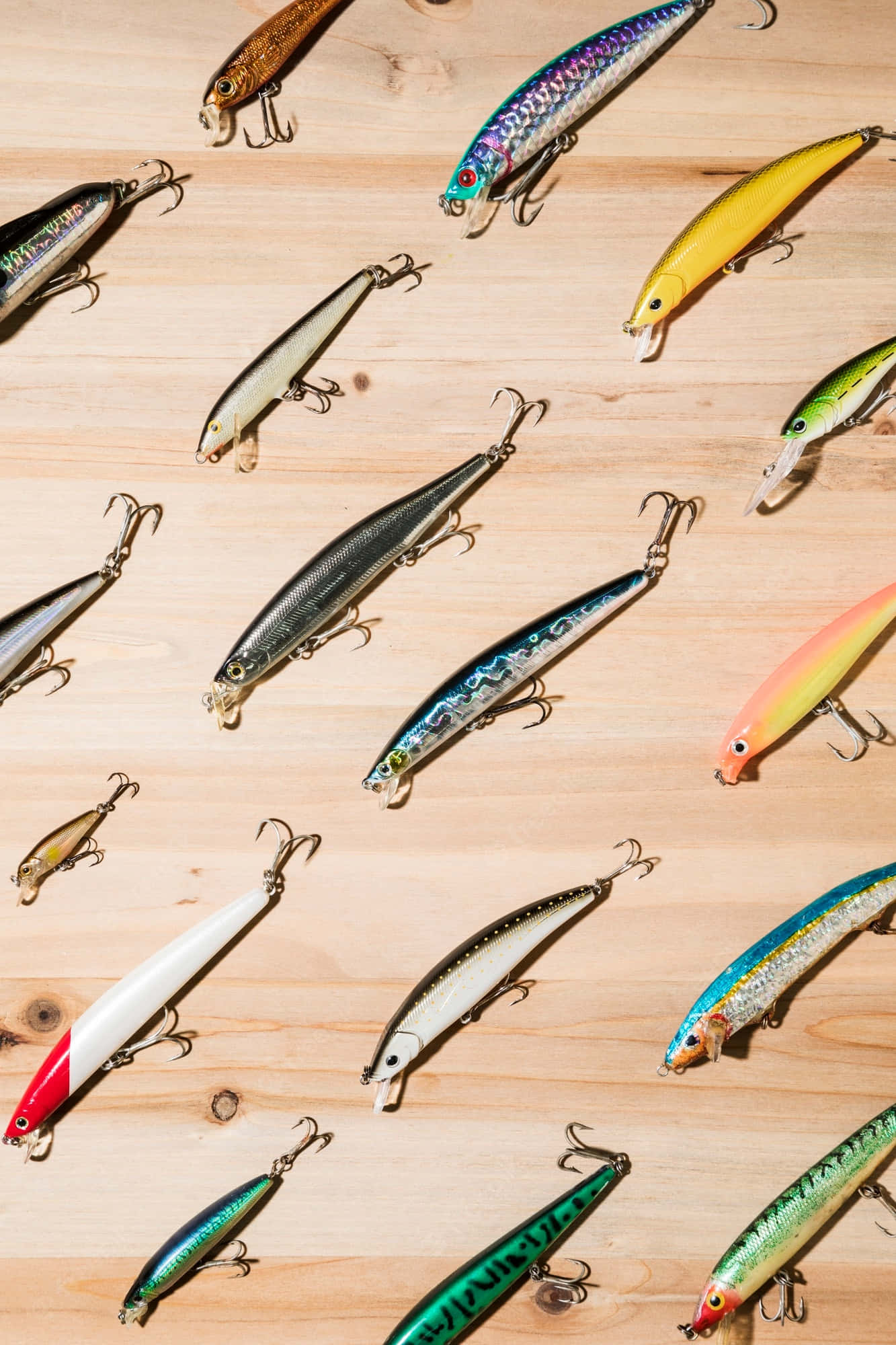 Fishing Bait 桌布 壁紙 — 鮮豔的魚餌以各種顏色和設計散落在淺色木質表面上。