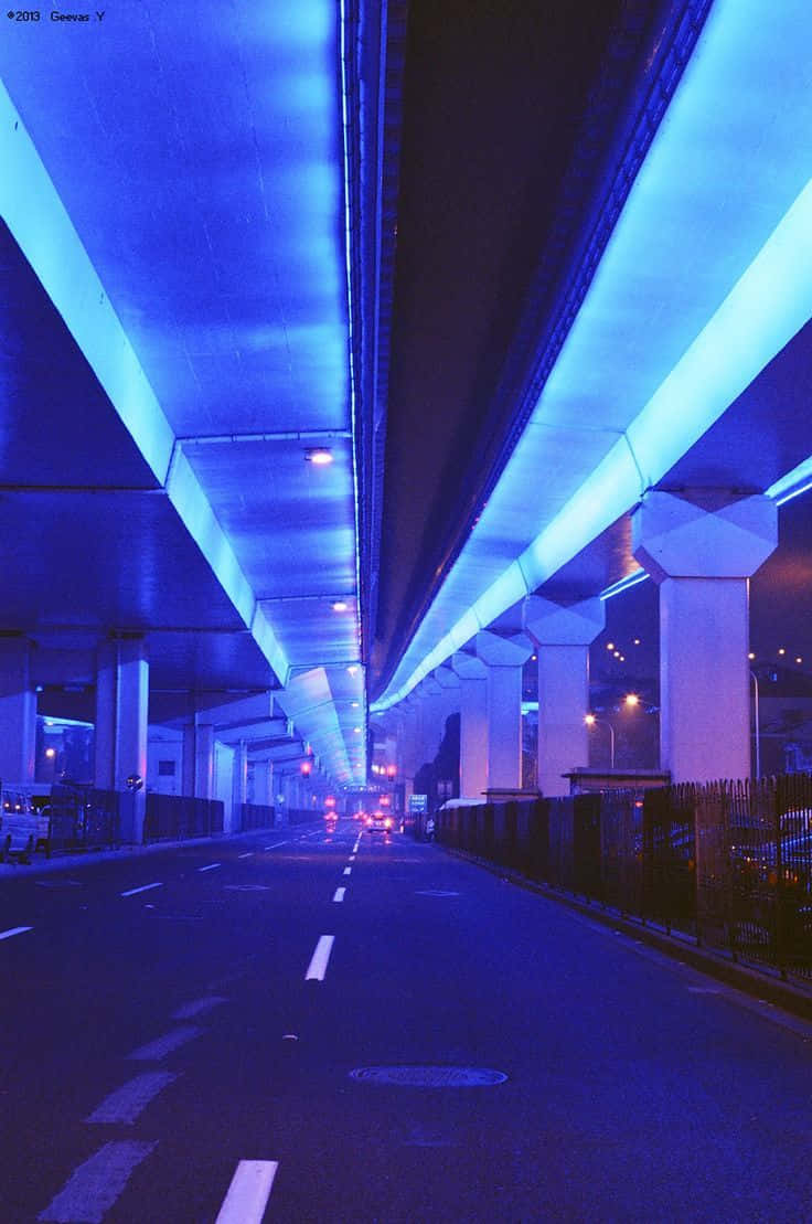 鮮豔霓虹藍色美學——黑暗中的光 壁紙 — 夜晚，一條被霓虹藍光照亮的高速公路地下通道，汽車逐漸消失在遠方。