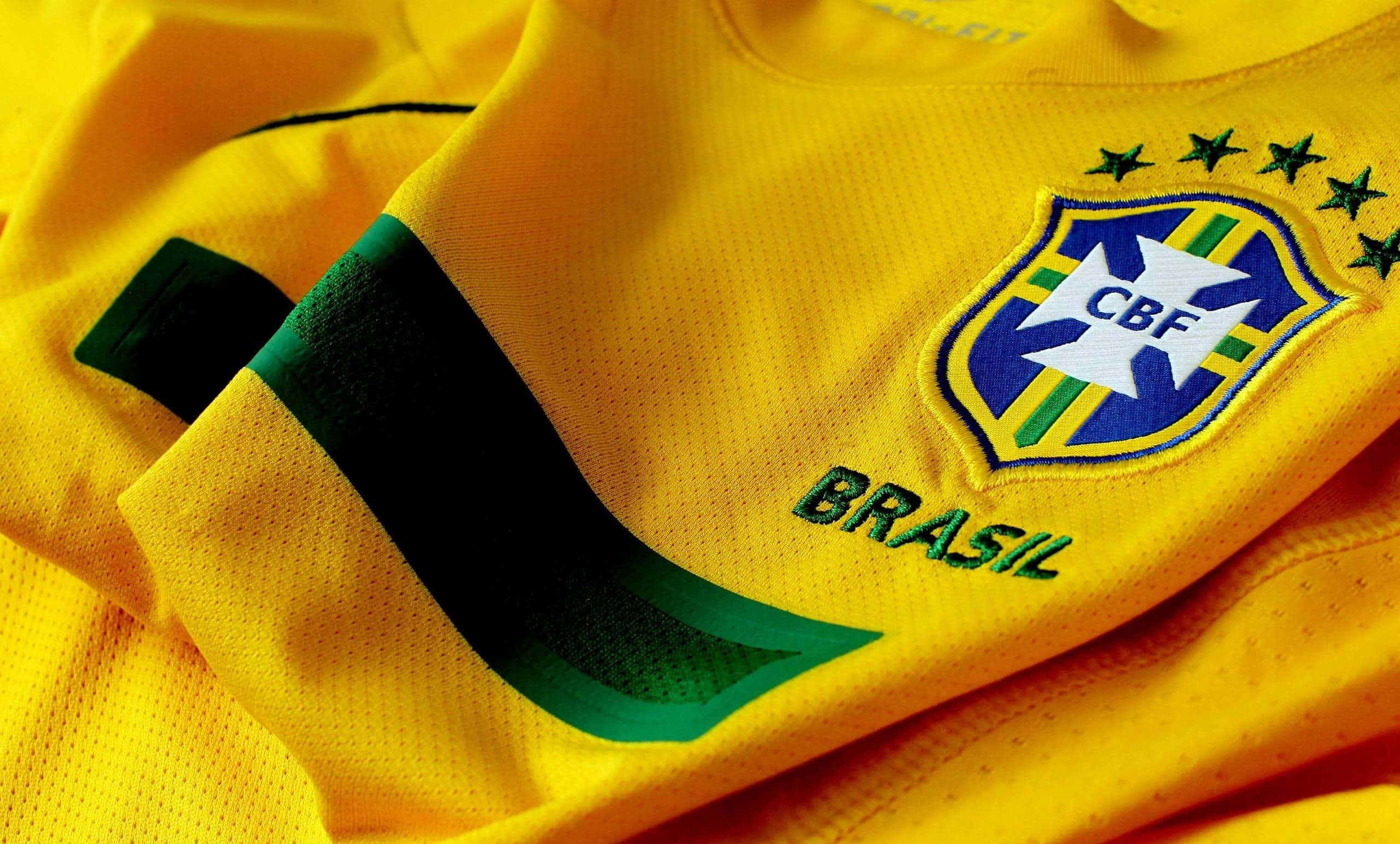 Brazil 桌布 壁紙 — 鮮黃色巴西足球球衣近距離特寫，帶有綠色點綴和刺繡CBF徽章。
