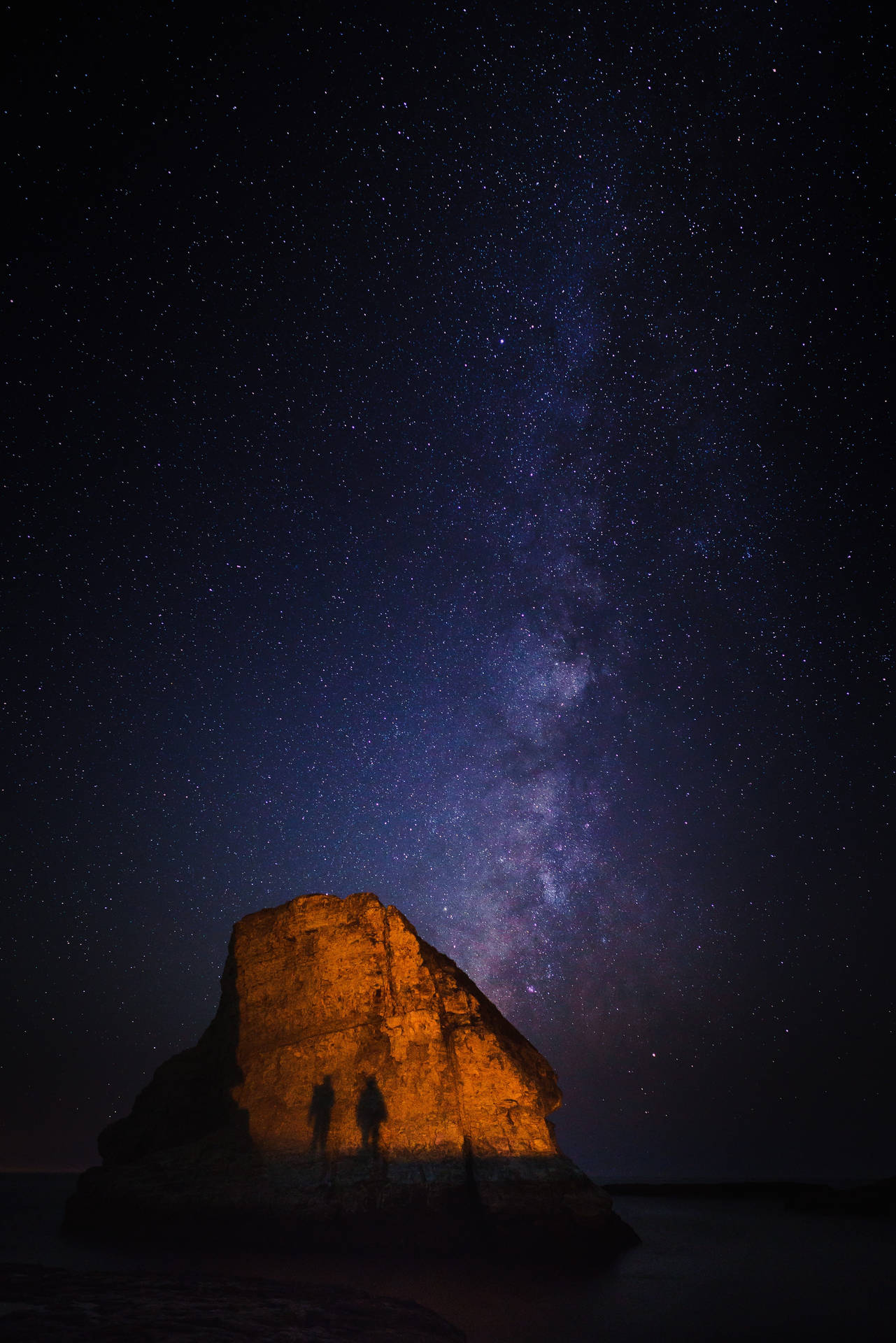 兩人在星空下站在發光的岩石上，銀河可見。