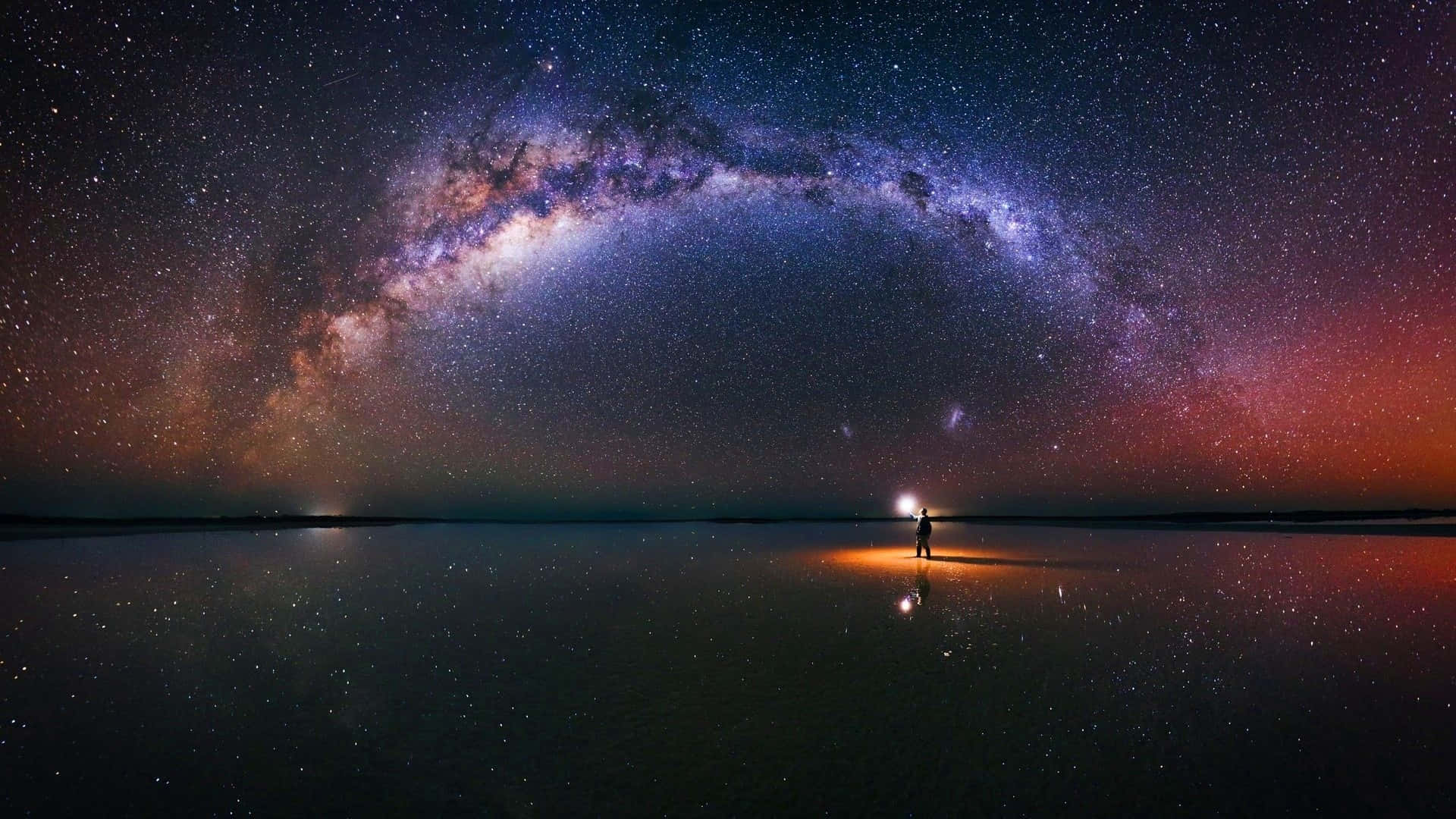 鹽湖上的銀河與星空背景 壁紙 — 一個孤獨的身影站在反射的鹽灘上，下方是令人嘆為觀止的銀河，橫跨星光燦爛的黃昏天空。