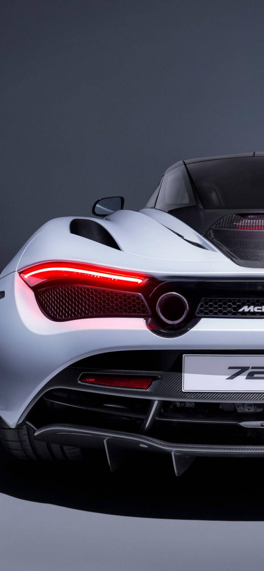 銀色McLaren 720S跑車後視圖，帶有紅色尾燈，在工作室中。