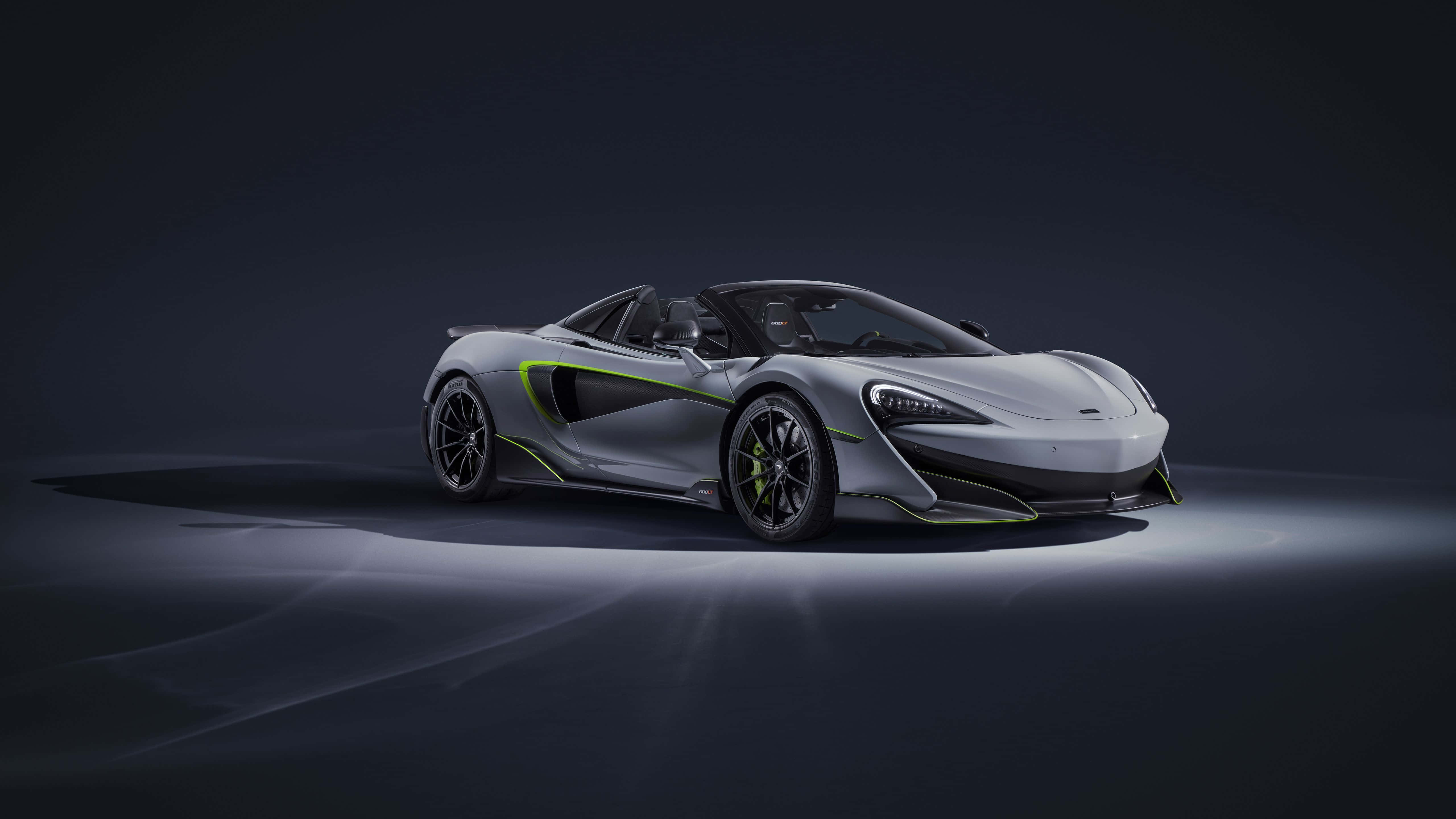 麥拉倫600LT 飛馳風采 壁紙 — 一輛時尚的銀色McLaren跑車帶有螢光綠色點綴，在黑暗背景下的戲劇性工作室燈光中閃耀。
