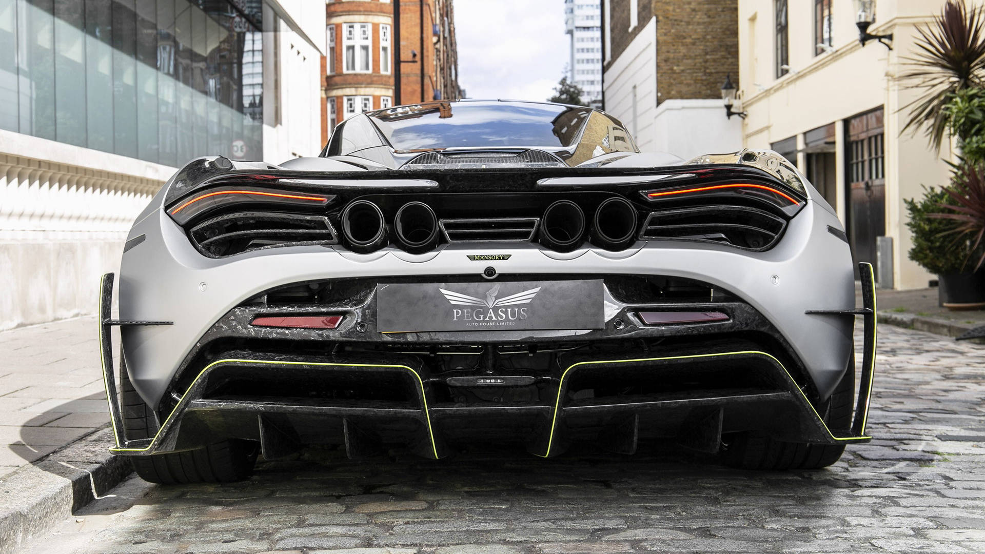 麥拉倫720S 4K：後視角度的強悍美學 壁紙 — 一輛銀色McLaren Pegasus超跑帶有黃色點綴，停泊在都市建築之間的鵝卵石街道上。
