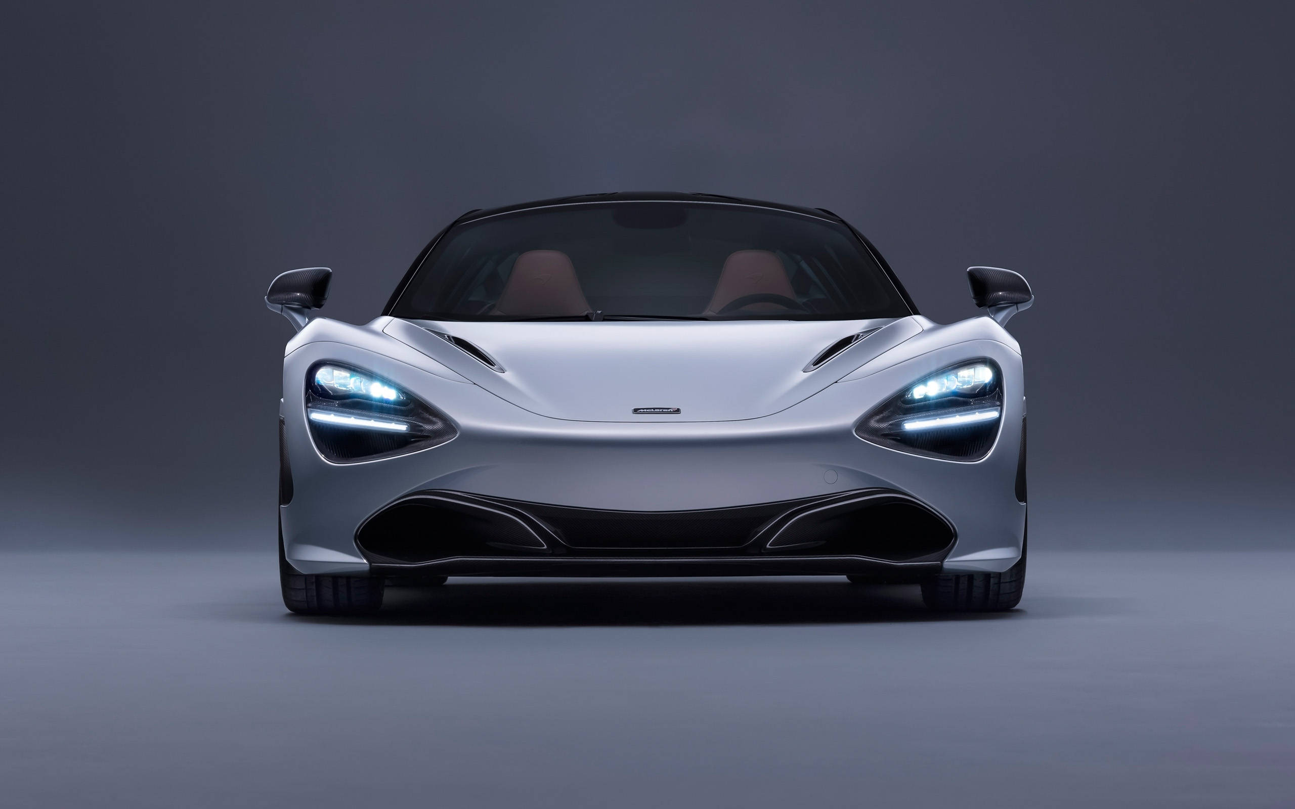 麥拉倫720s 4K車頭視角 壁紙 — 一輛時尚的銀色麥拿侖跑車，車頭燈發光，正面朝向深灰色工作室背景。
