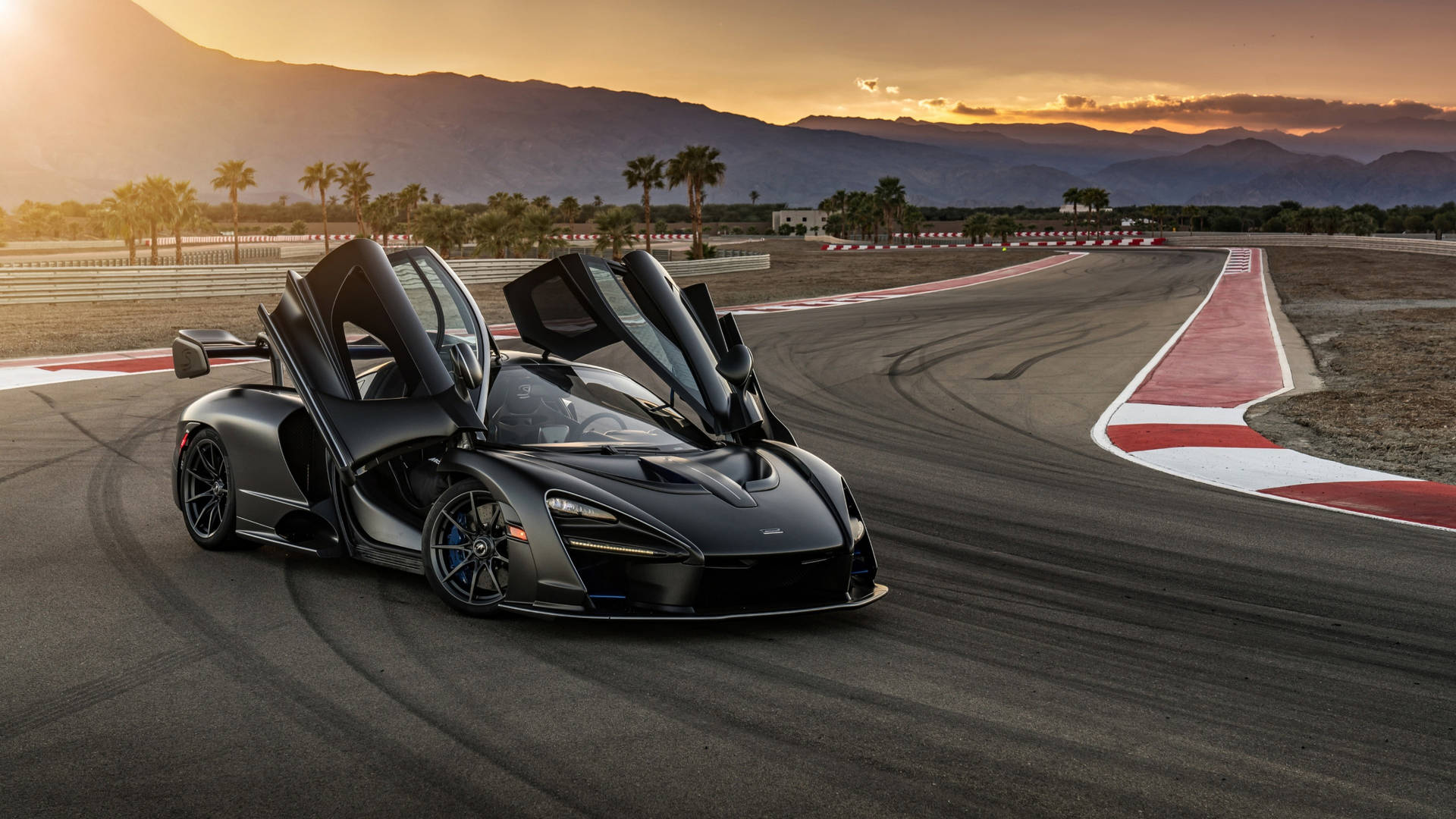 黑色McLaren Senna在賽車場上，車門打開，日落時分。