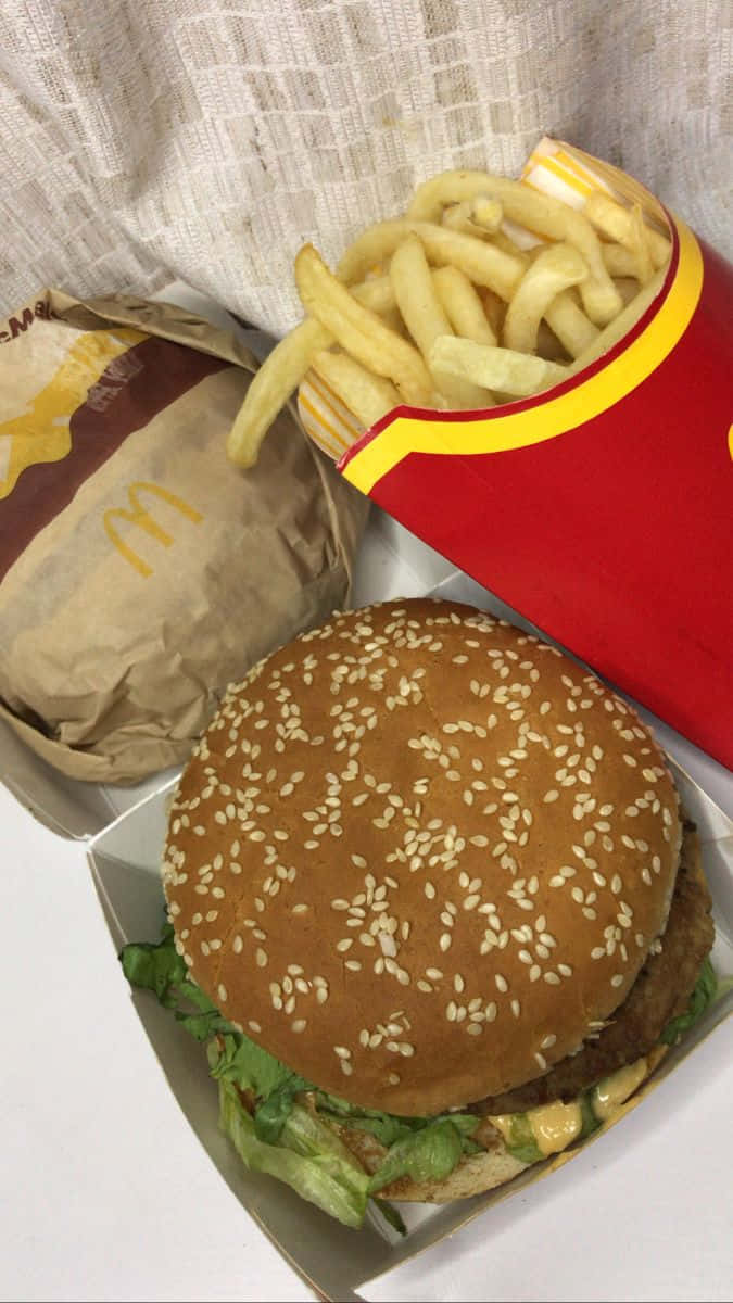 麥當勞漢堡與法式薯條 壁紙 — 白色表面上，帶有芝麻的麥當勞漢堡和薯條，採用品牌包裝的特寫。