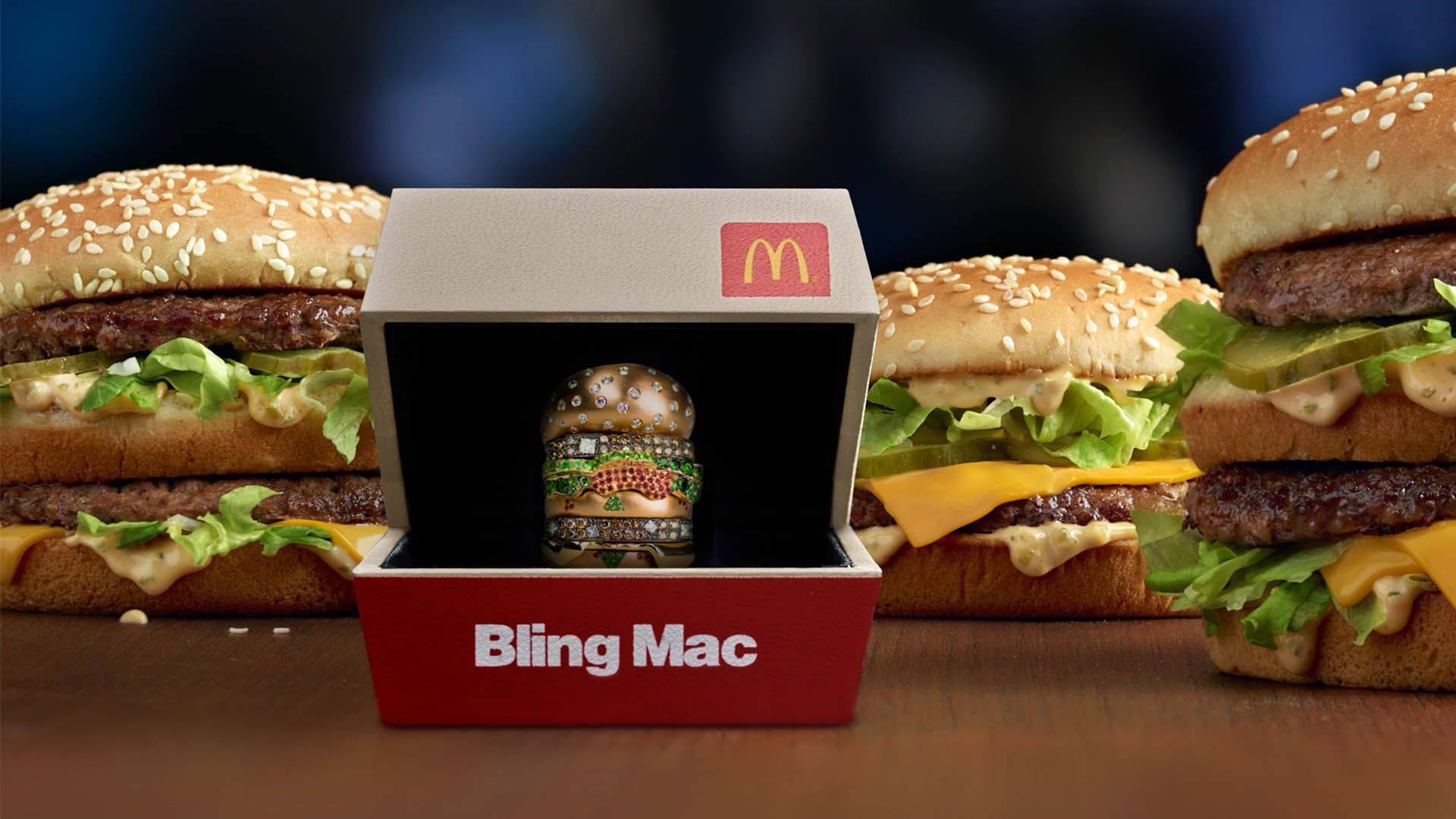 麥當勞閃耀巨無霸 壁紙 — 一個麥當勞Bling Mac漢堡公仔喺紅色盒入面閃閃發光，周圍係木枱上嘅真芝麻漢堡。