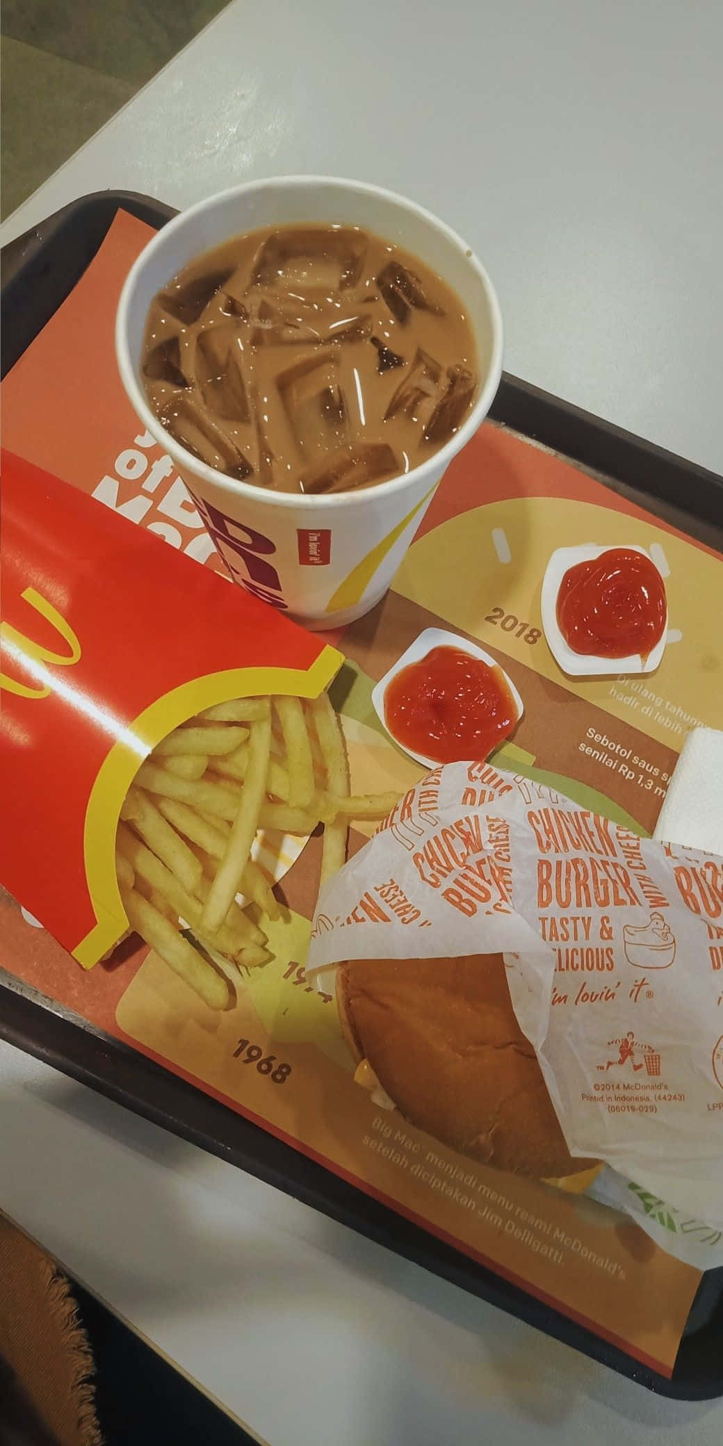 麥當勞餐盤上的漢堡與薯條 壁紙 — 一個麥當勞餐盤上放著一杯加冰的凍咖啡、一個包裝好的漢堡、薯條和茄汁包。