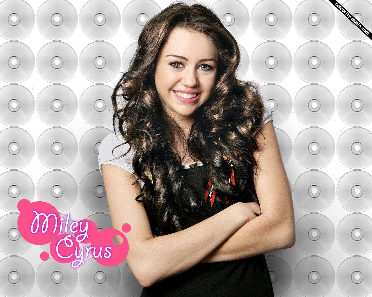 Miley Cyrus 在CD背景前微笑，雙臂交叉。