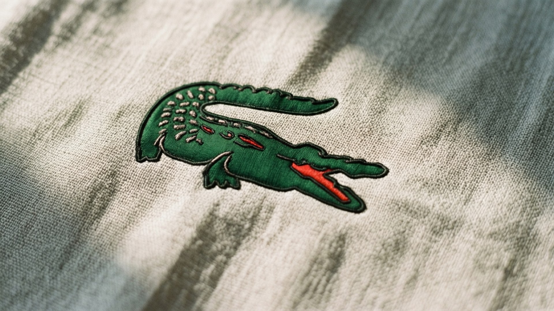 米色布料上的綠色刺繡鱷魚標誌，帶有陽光陰影。