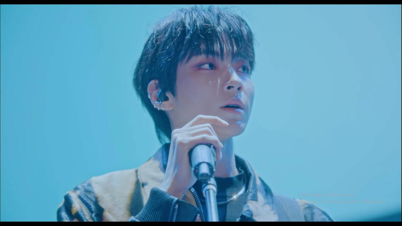 黃仁燦飾演韓世俊 壁紙 — 一位年輕男歌手臉上掛著淚痕，在冰冷的藍色舞台燈光下握著麥克風。