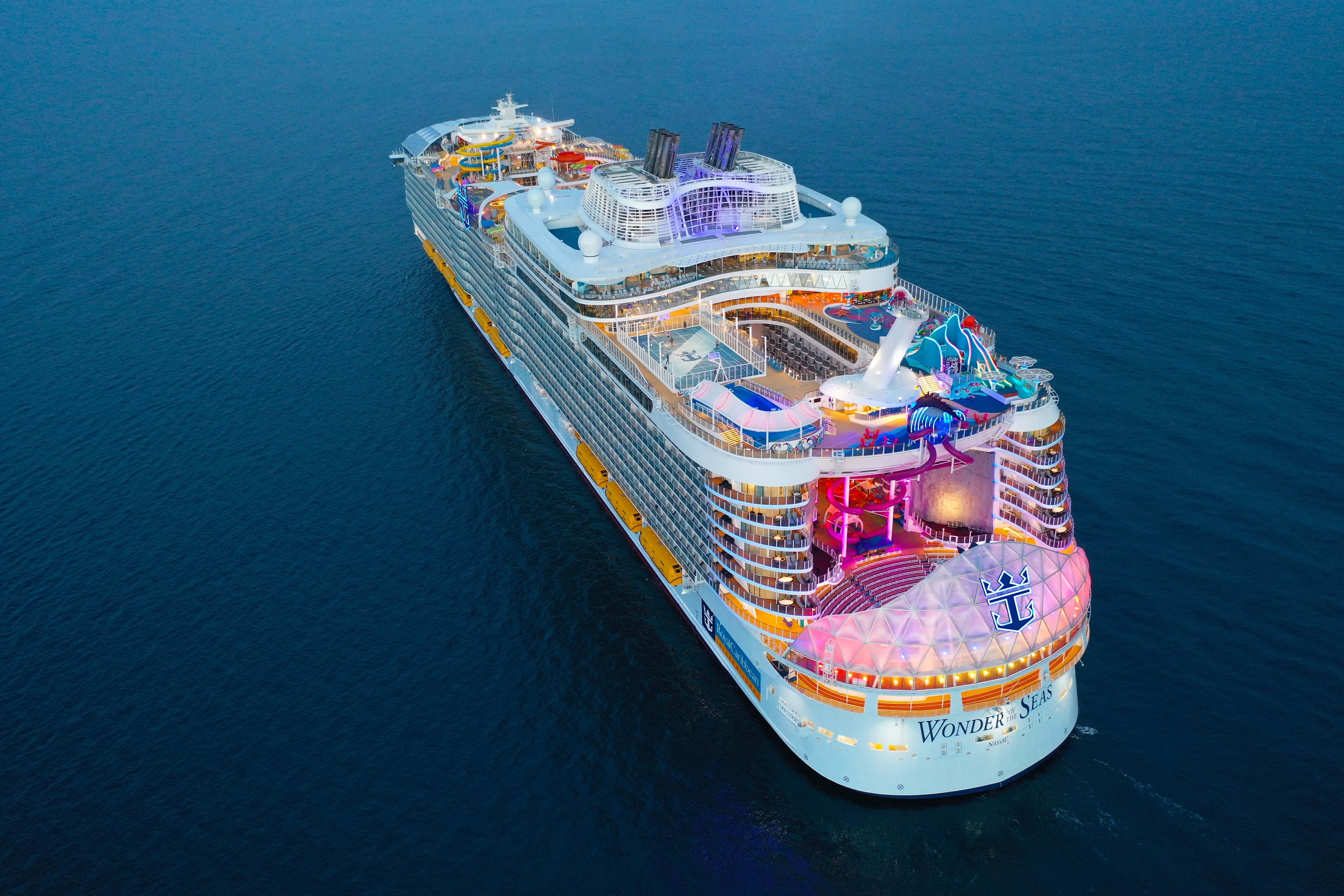 Cruise Ship 桌布 壁紙 — 黃昏時分，Wonder of the Seas 郵輪在深藍色海洋上閃爍著彩色燈光的鳥瞰圖。