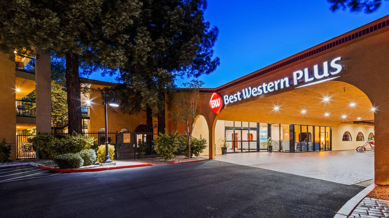 夜晚的 Best Western Plus 酒店入口，帶有發光招牌和樹木。
