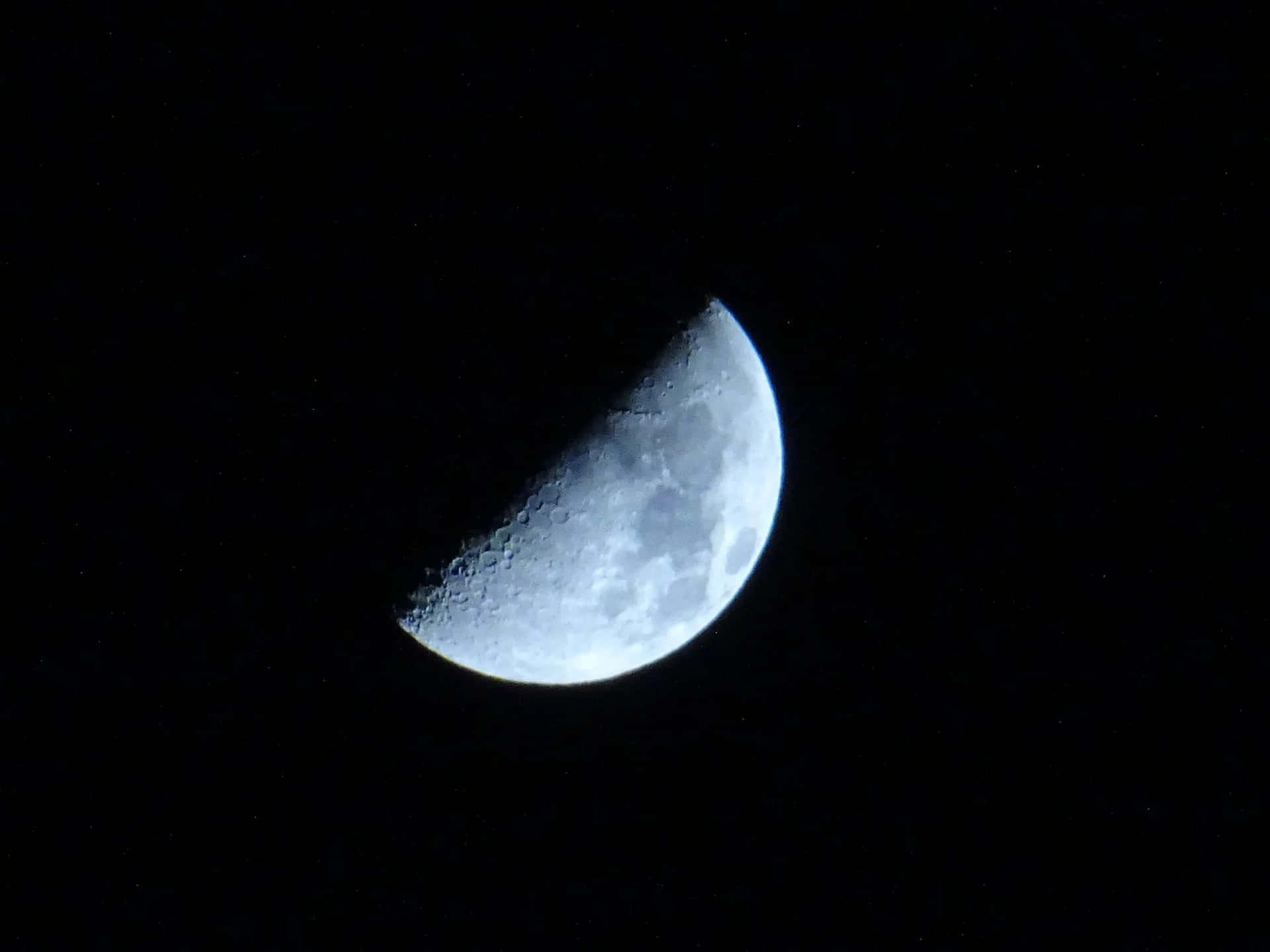 彎月與可見的隕石坑，背景是繁星點點的夜空