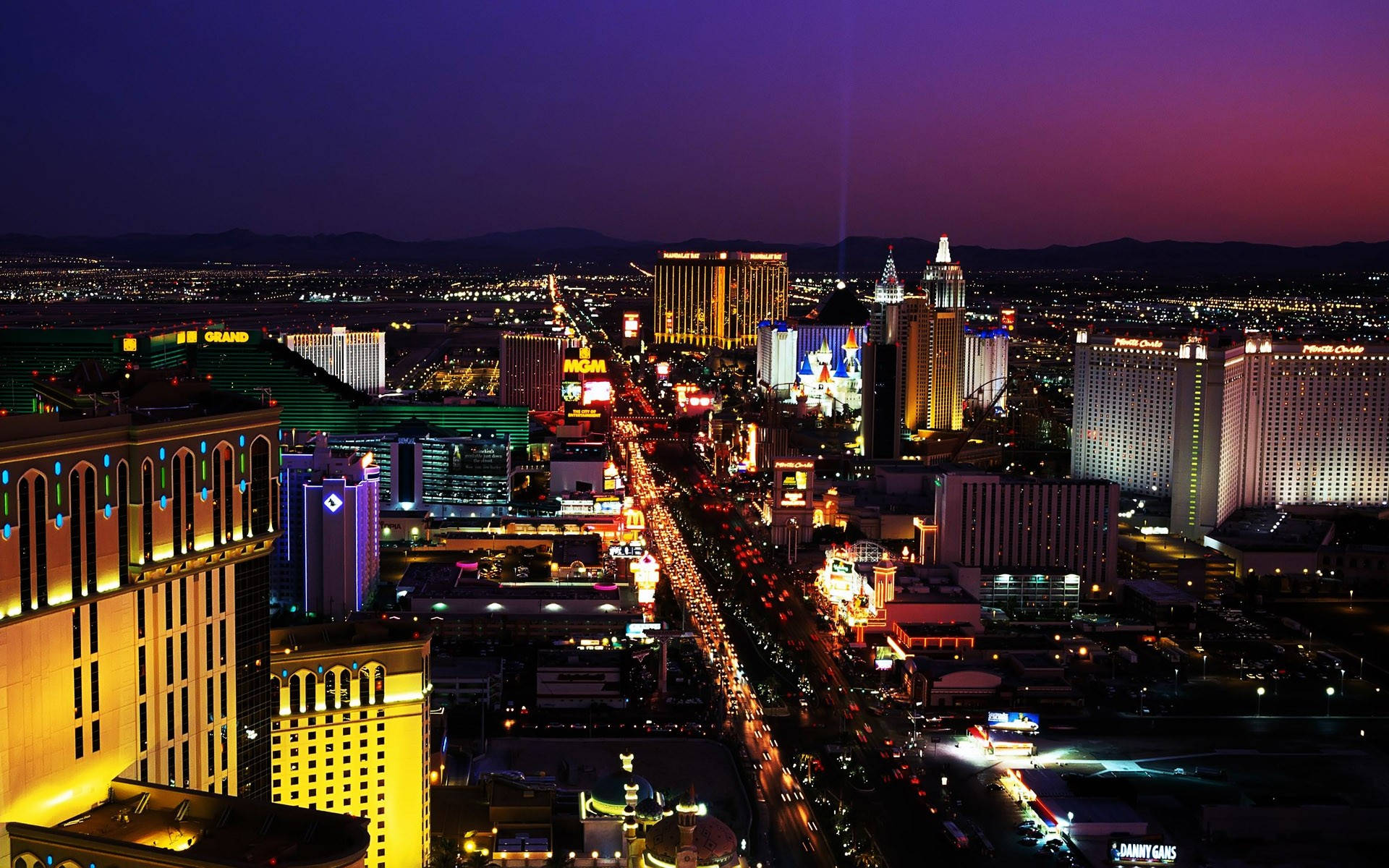 Las Vegas Night 桌布 壁紙 — 黃昏時分拉斯維加斯大道上空鳥瞰，紫色天空下閃爍的賭場酒店和車流燈光。