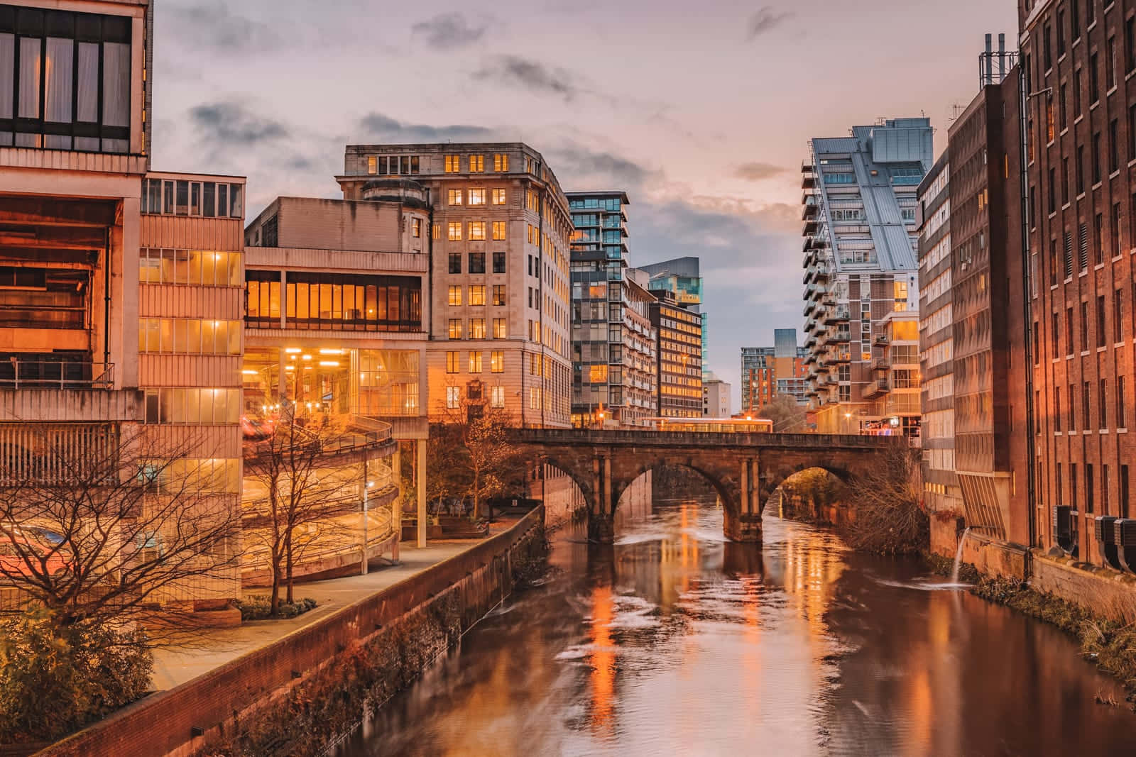 England 桌布 壁紙 — 黃昏時分的城市河流，溫暖的燈光在現代與歷史建築之間的水面上反射。