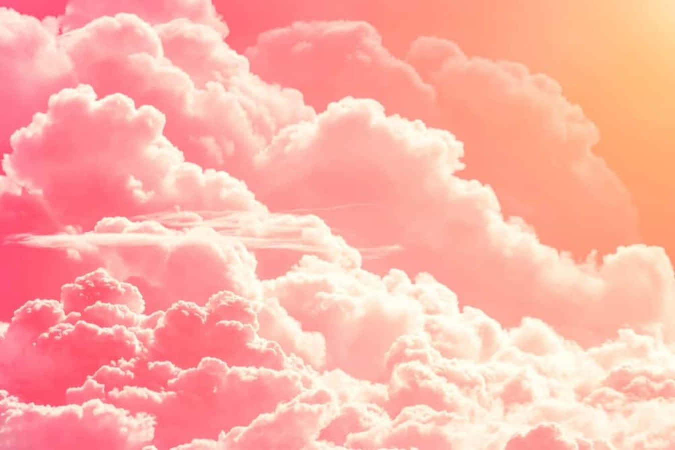 「黃昏時分粉紅雲朵的超現實之美」 壁紙 — 廣闊如棉的雲朵在溫暖漸變的天空中散發著柔和的粉紅和蜜桃色調。