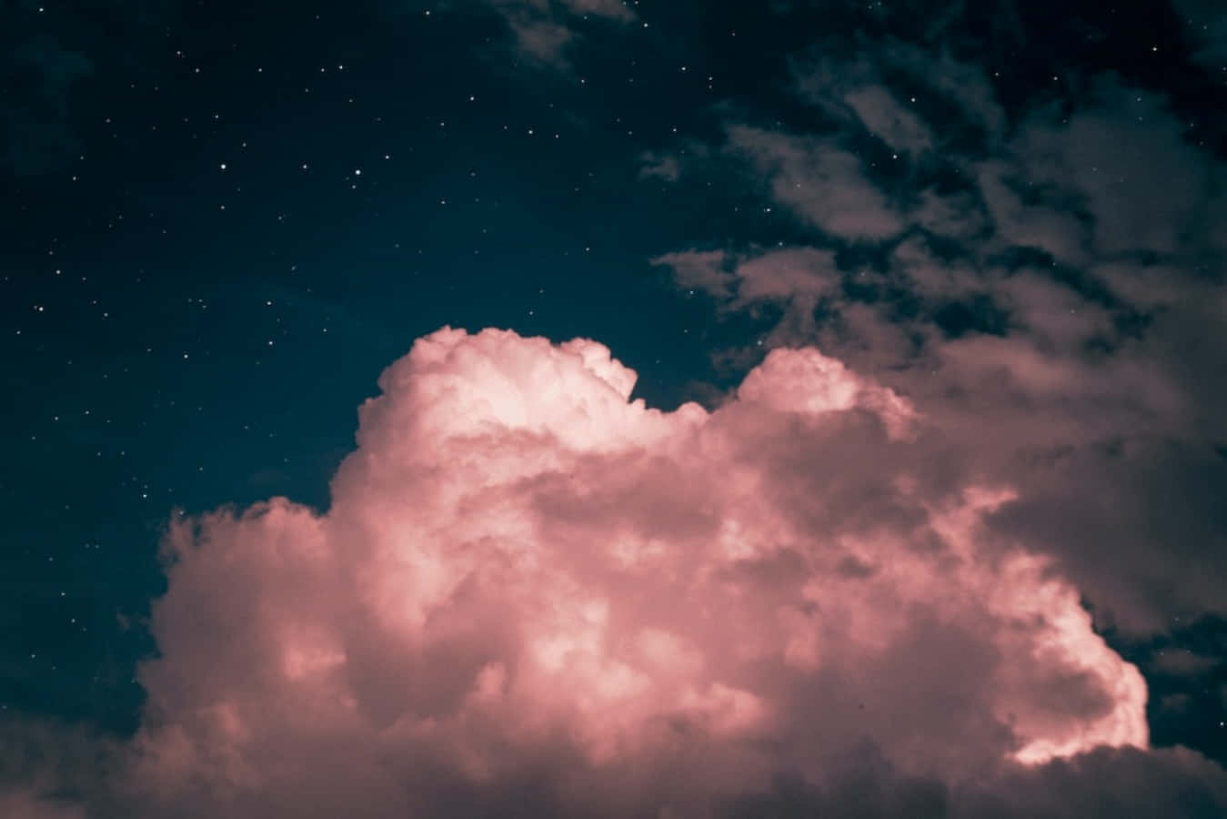 黃昏粉紅雲朵畫 壁紙 — 巨大的粉紅色雲朵在繁星點點的夜空下被照亮，帶有深藍綠色調。