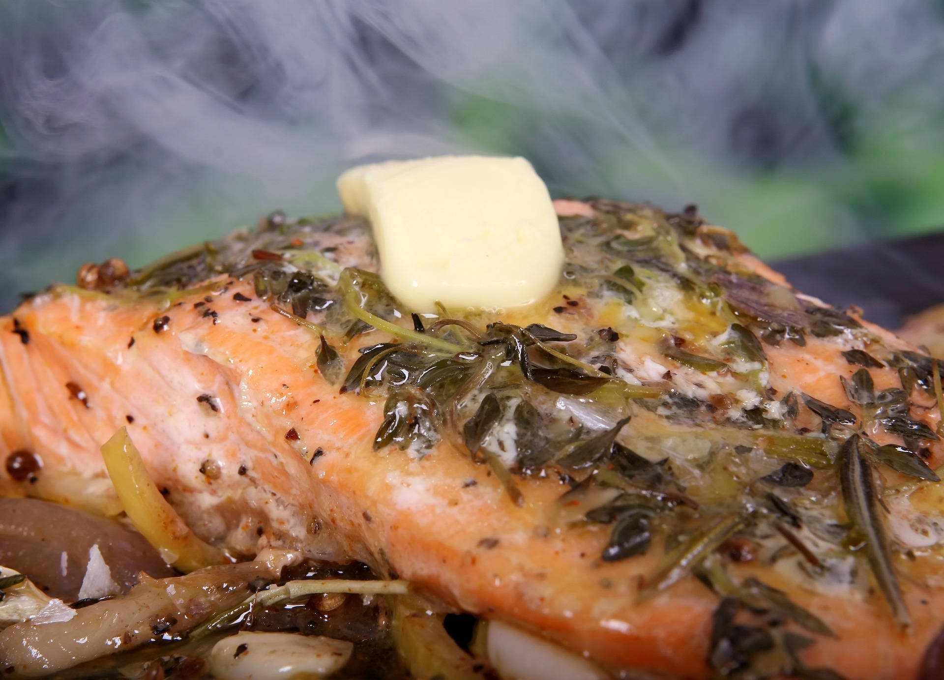 黃油海 bass 魚 壁紙 — 一塊蒸氣騰騰的香草調味三文魚，上面放著融化的牛油，並以迷迭香點綴。