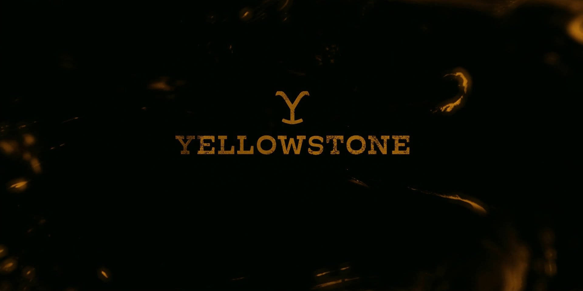 黃石電視劇標誌 壁紙 — 金色嘅 Yellowstone 標誌喺黑暗紋理背景上發光，周圍有熾熱嘅火花漂浮。