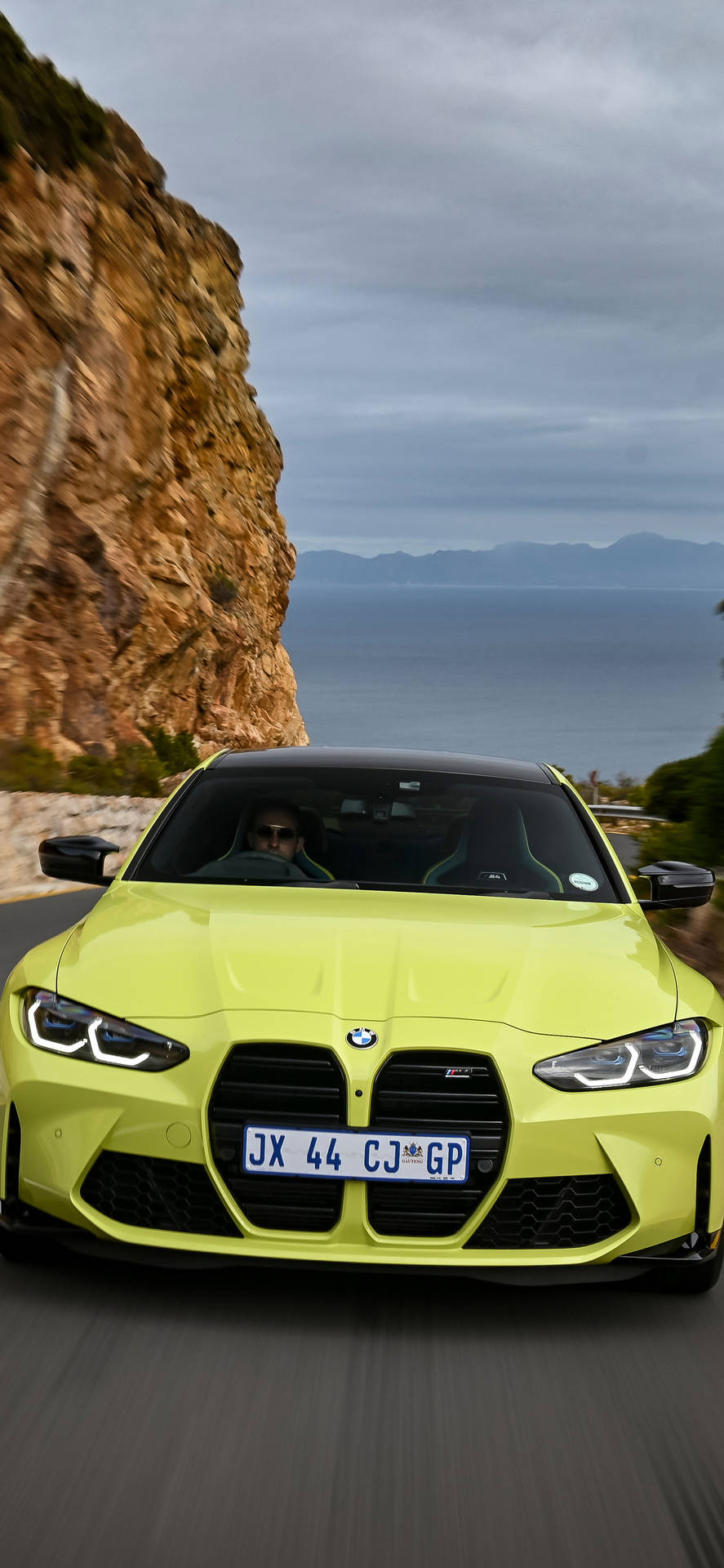 青檸綠色BMW M4在海岸懸崖道路上疾馳，享有海景。