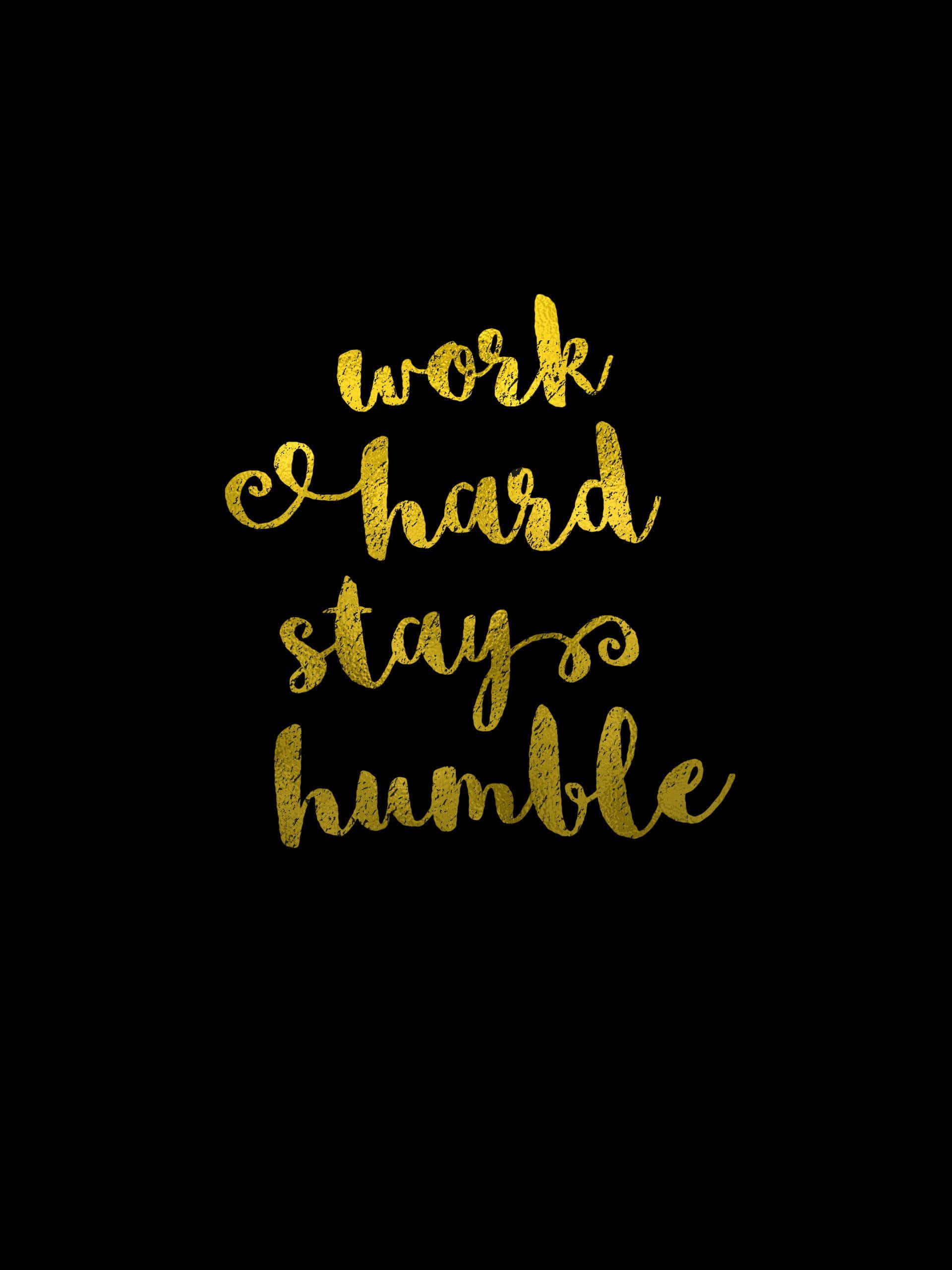 黃色「保持謙卑」標語 壁紙 — 金色閃亮草書文字「work hard stay humble」居中於純黑色背景上。