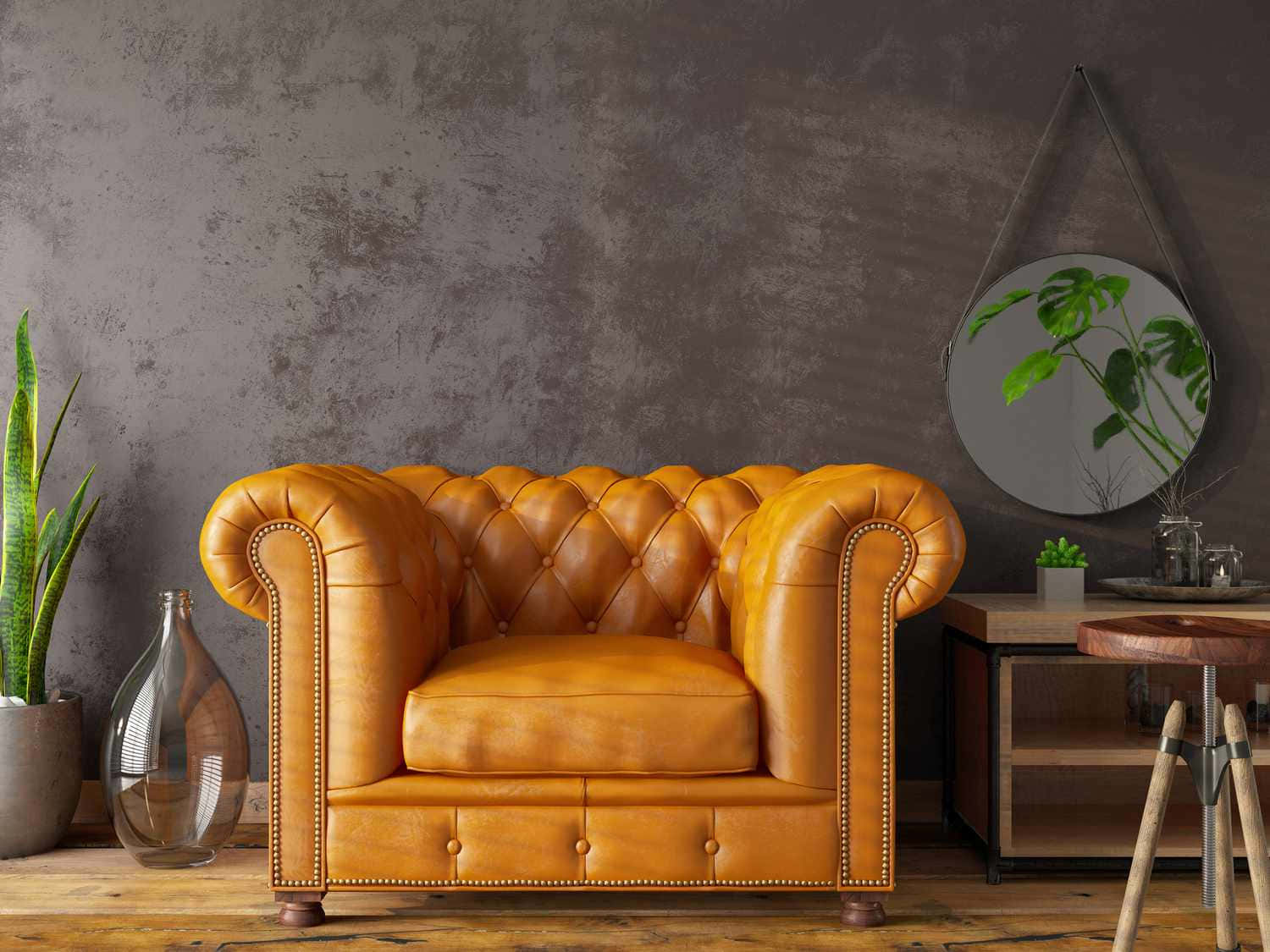 黃色皮革扶手閱讀椅 壁紙 — 一張豐富的琥珀色簇絨皮革 Chesterfield 沙發位於質樸的工業風房間，配有紋理灰色牆壁和木地板。