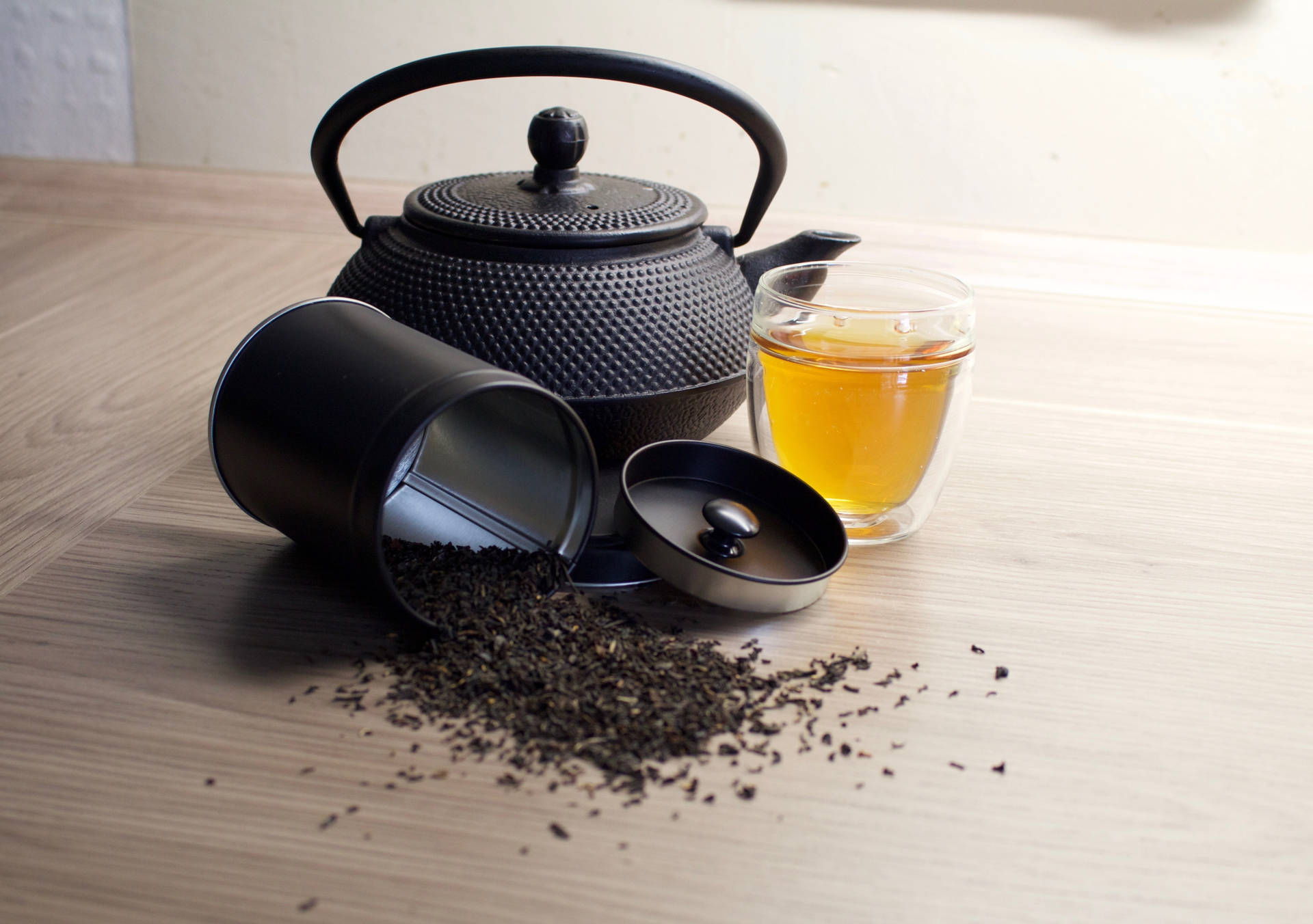 黑色茶壺與灑出的茶葉和一杯茶在木桌上
