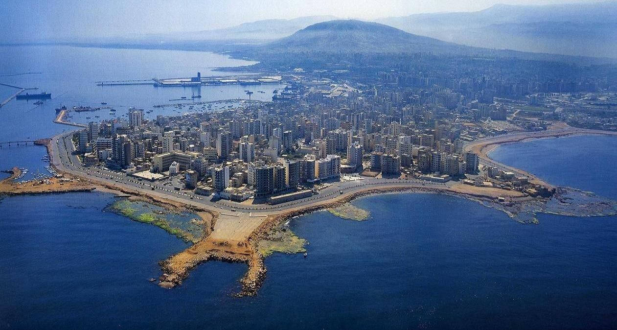 黎巴嫩城市與山脈 壁紙 — 沿海城市的鳥瞰圖，坐落於深藍色水域與遠處山脈之間，天空晴朗。