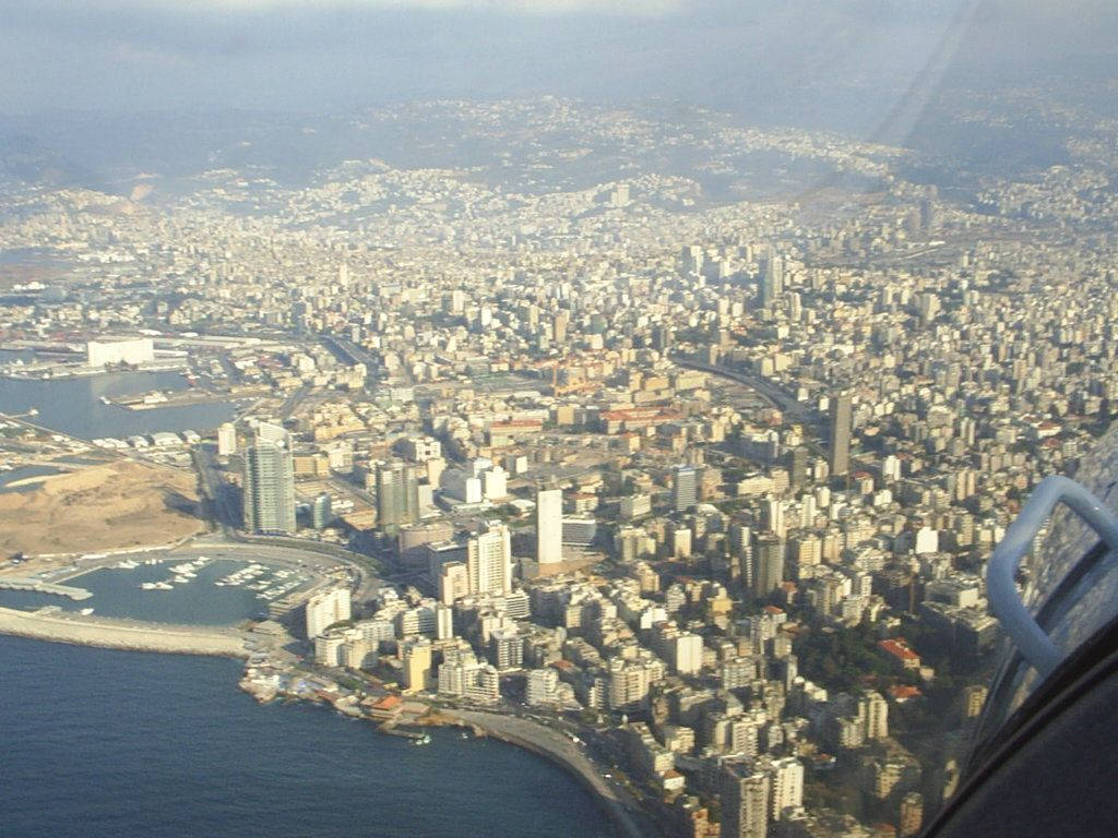 黎巴嫩直升機俯瞰 壁紙 — 從高空俯瞰沿海城市，密集的建築物緊貼海岸線和碼頭，在朦朧的日光下。