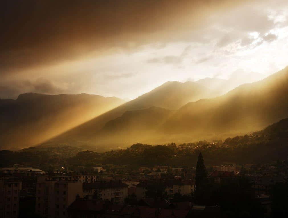 Sepia 桌布 壁紙 — 黎明時分，金色陽光穿透暴風雲層，照耀在山城之上。