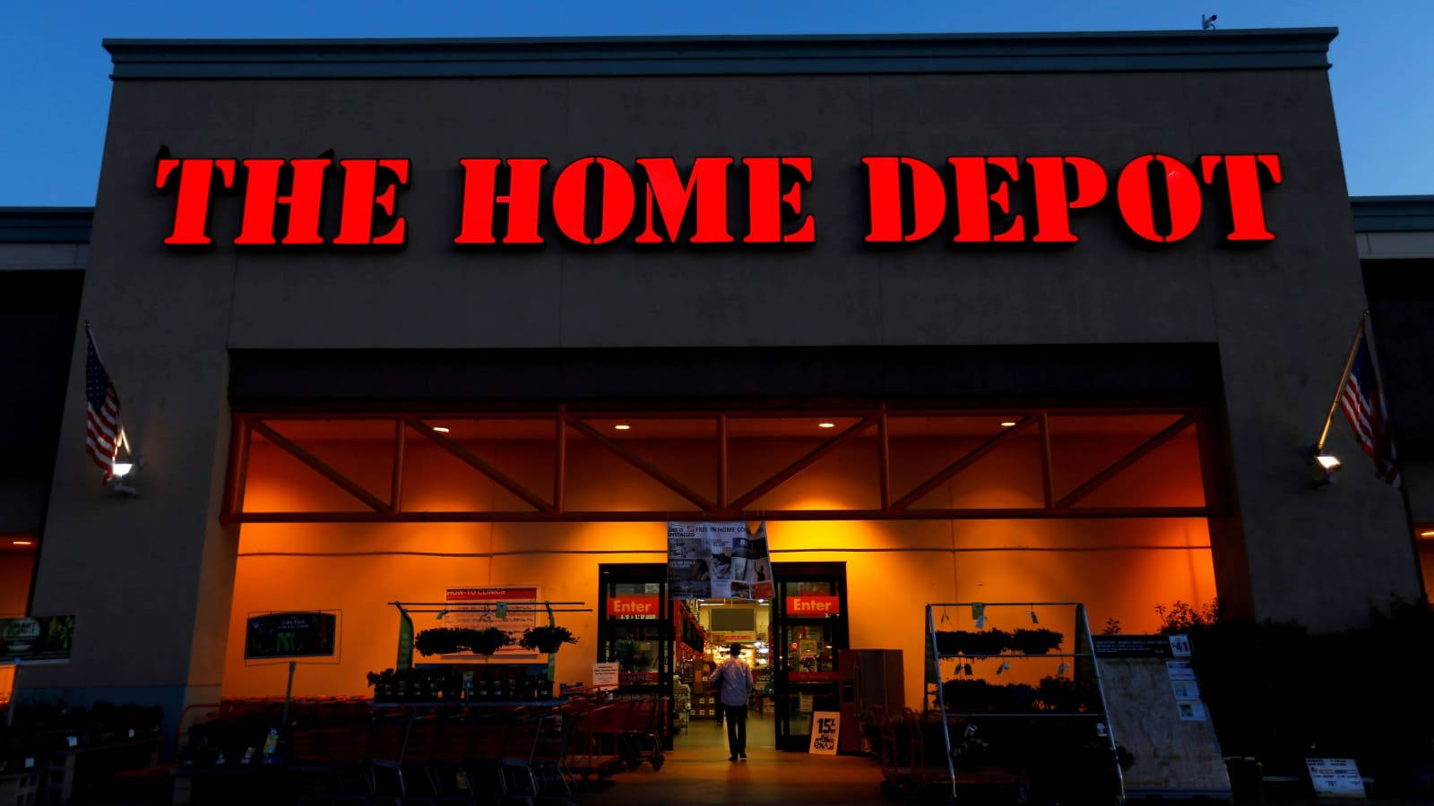 Home Depot 商店正面在黃昏時亮起，帶有紅色標誌和美國國旗。