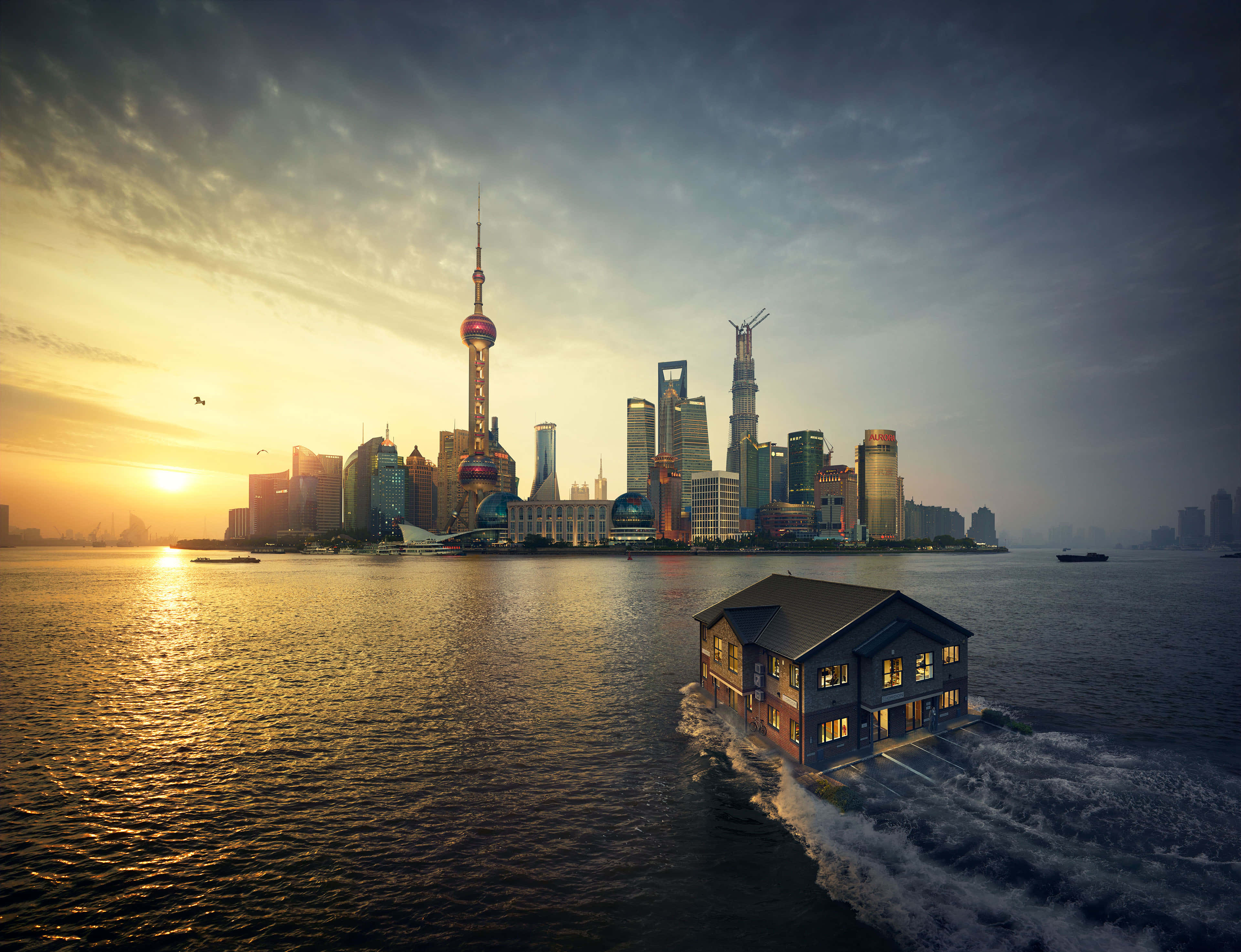 黎明時分的海灘 壁紙 — 一座漂浮的房子在日落時分滑過水面，背後是上海標誌性的天際線閃耀著光芒。