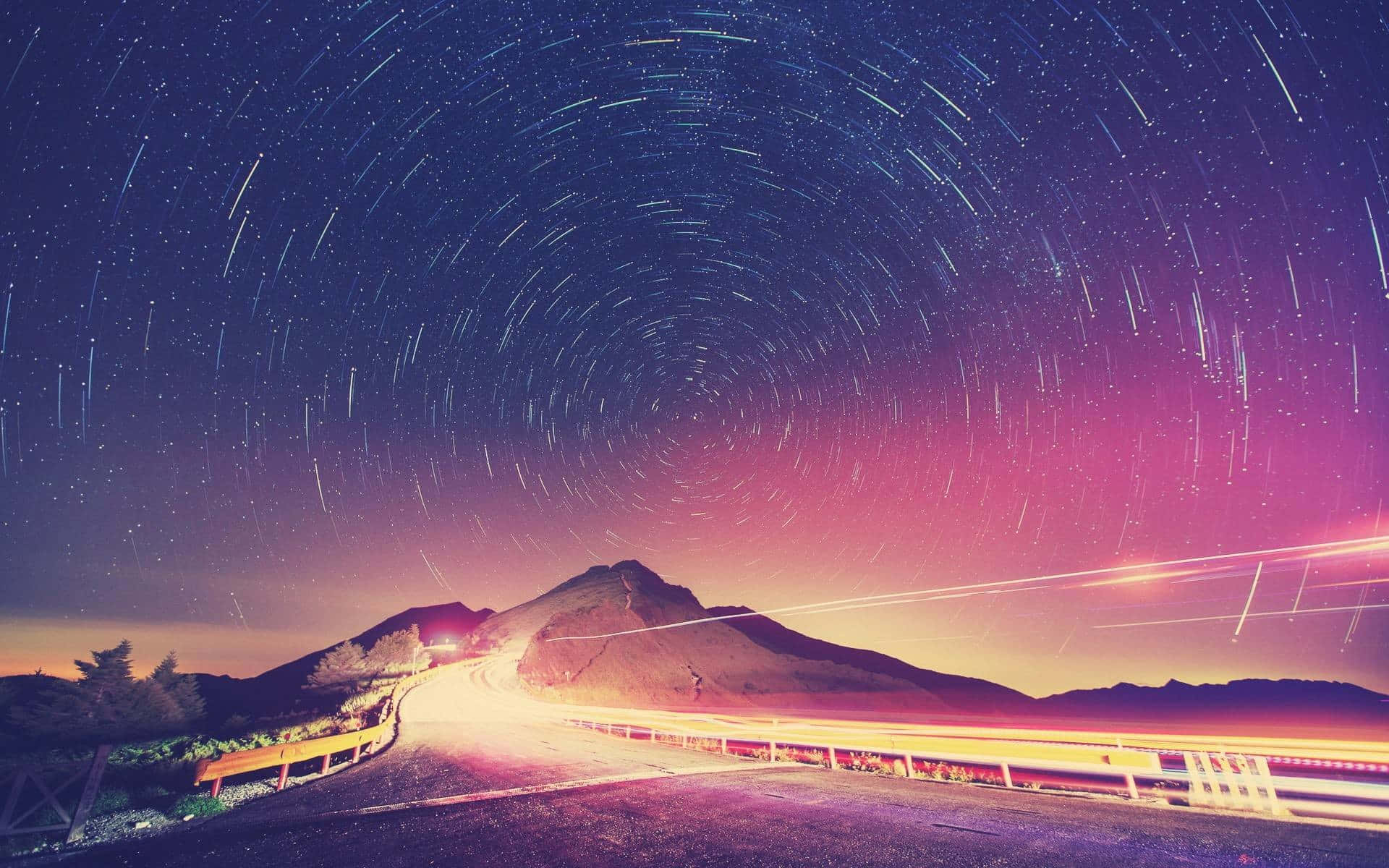 夜晚蜿蜒的山路，帶有星軌和車輛光條。