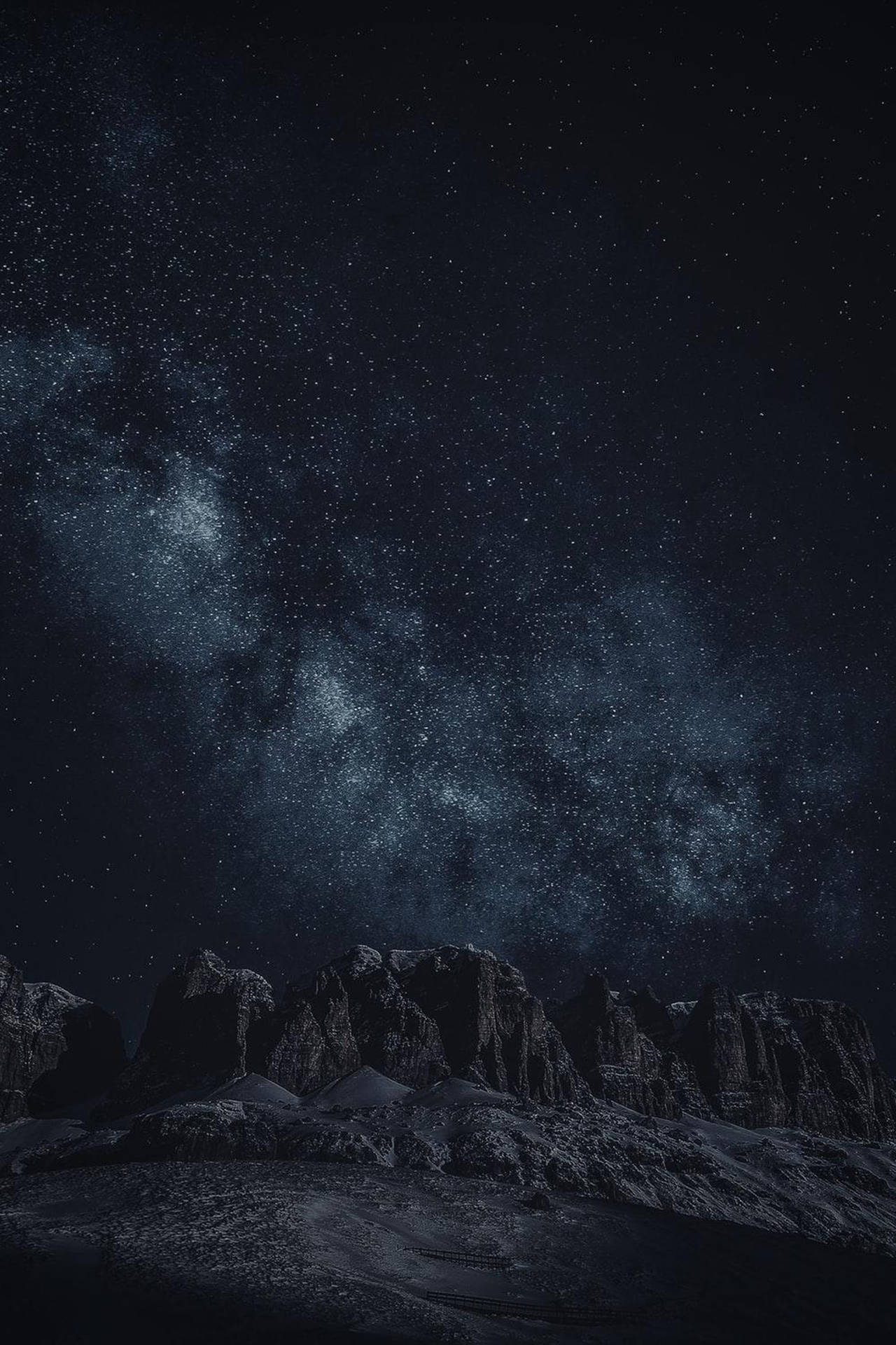 積雪的山脈在繁星點點的夜空下，銀河清晰可見。