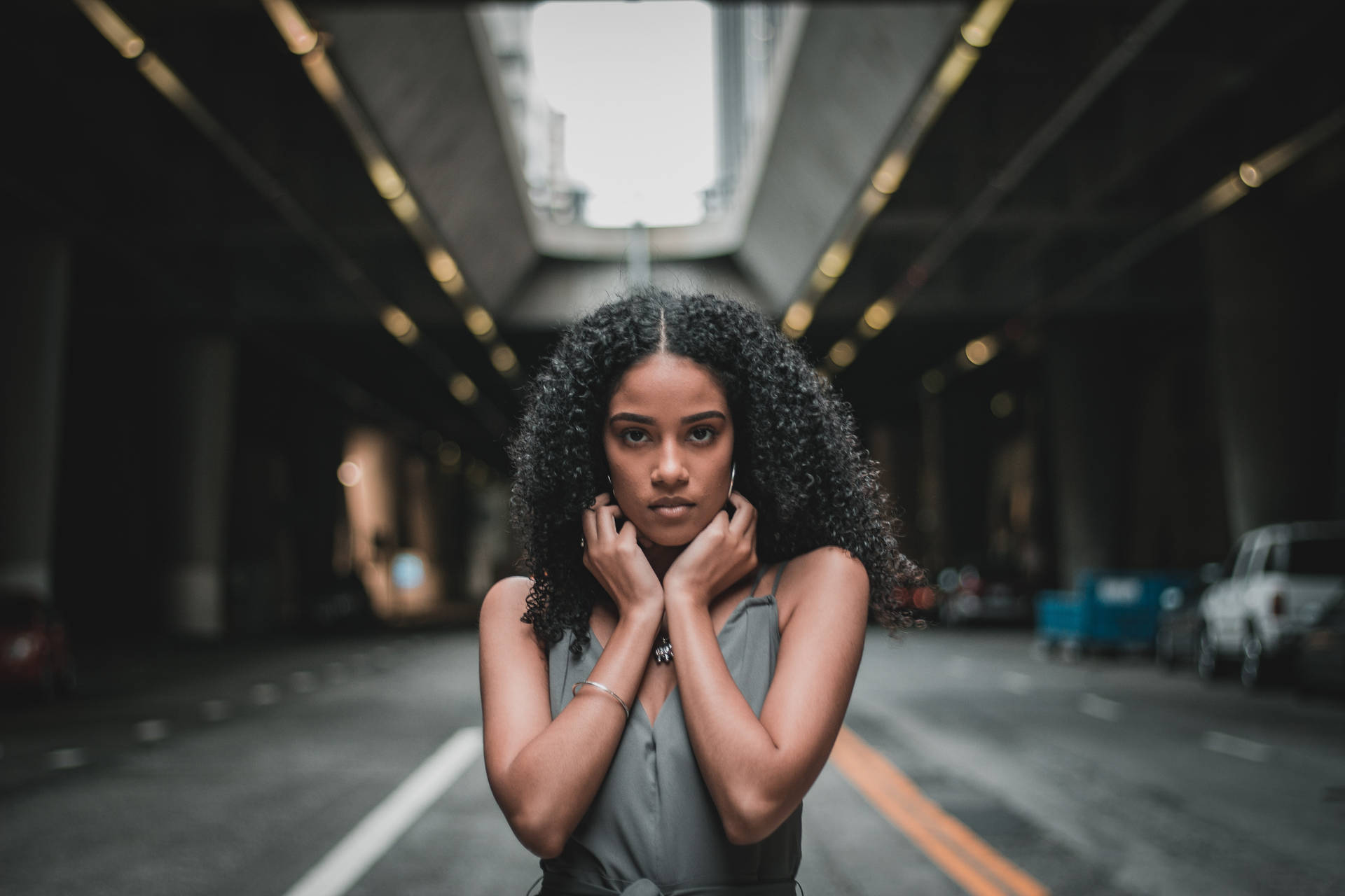 一位捲髮女士站在昏暗的城市隧道中看著鏡頭。