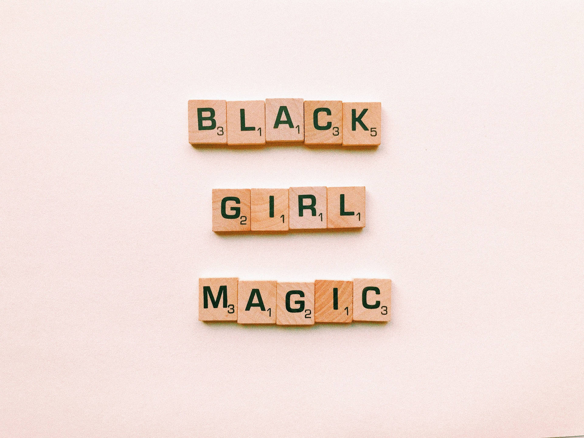 木製 Scrabble 字母磚排列在米色表面上拼出 Black Girl Magic。