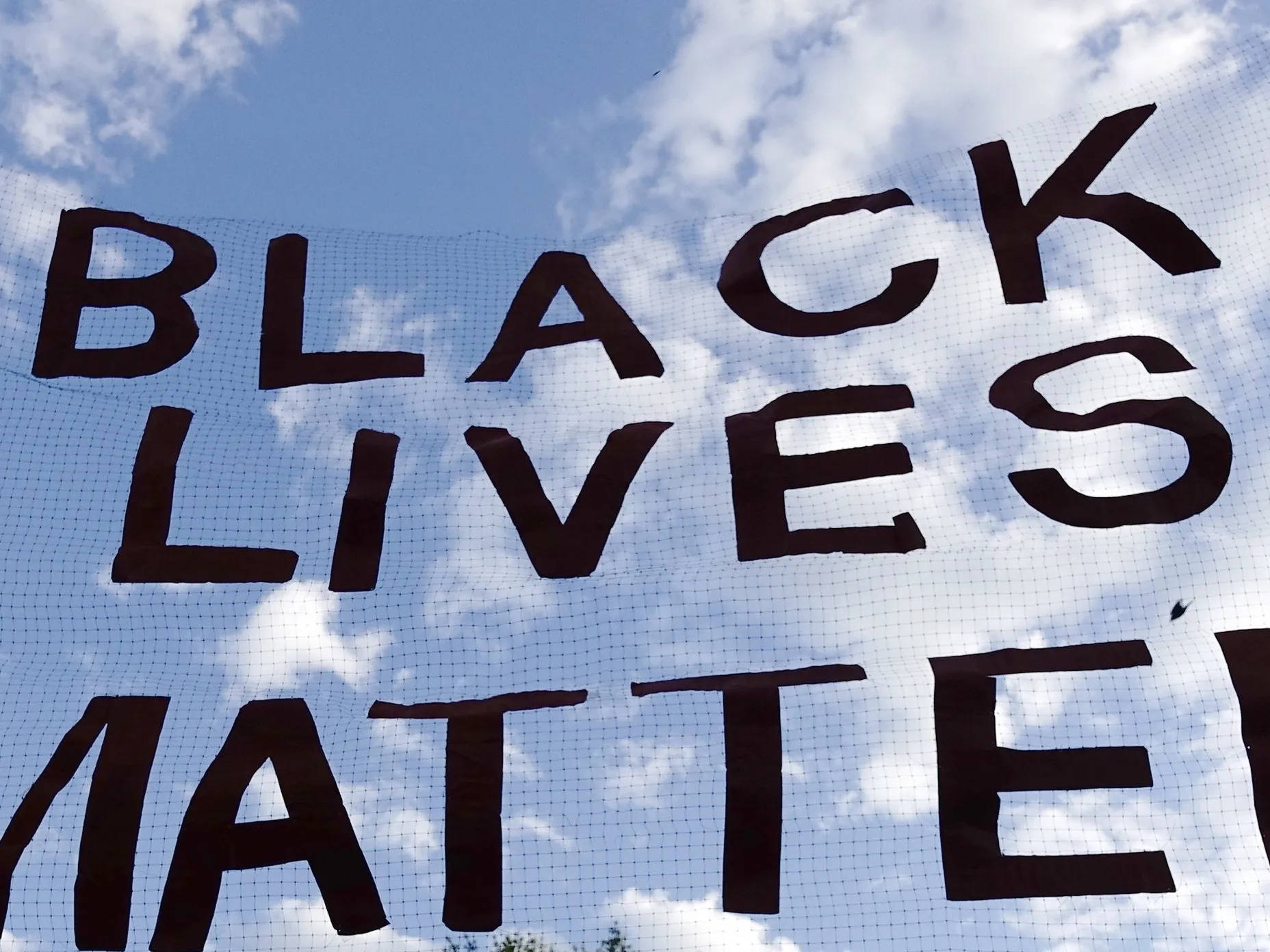 Black Lives Matter 抗議標語牌在藍天白雲下。