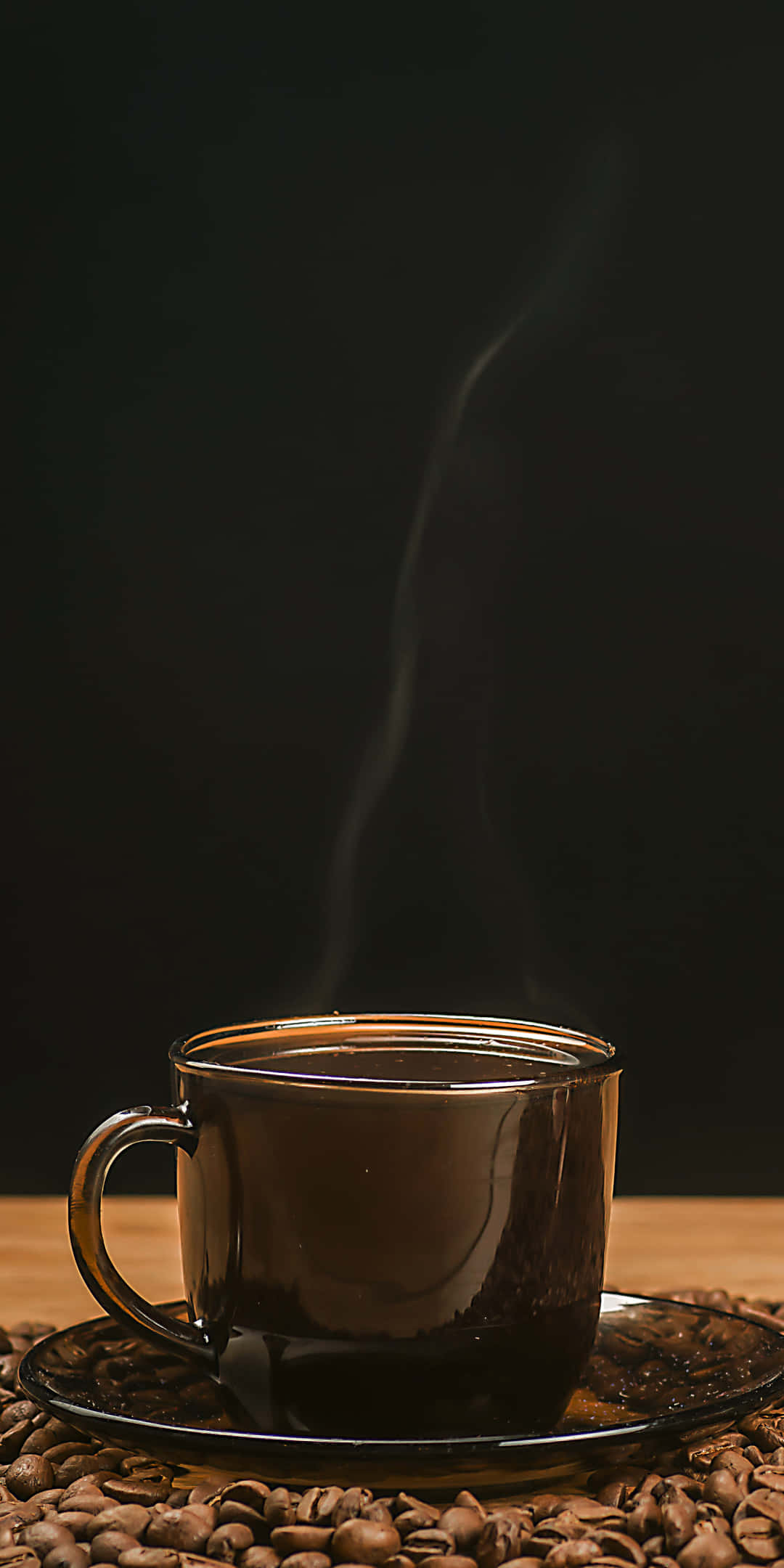 黑咖啡杯圖片 壁紙 — 一杯冒煙的咖啡放在碟子上，周圍環繞著咖啡豆，背景深色。