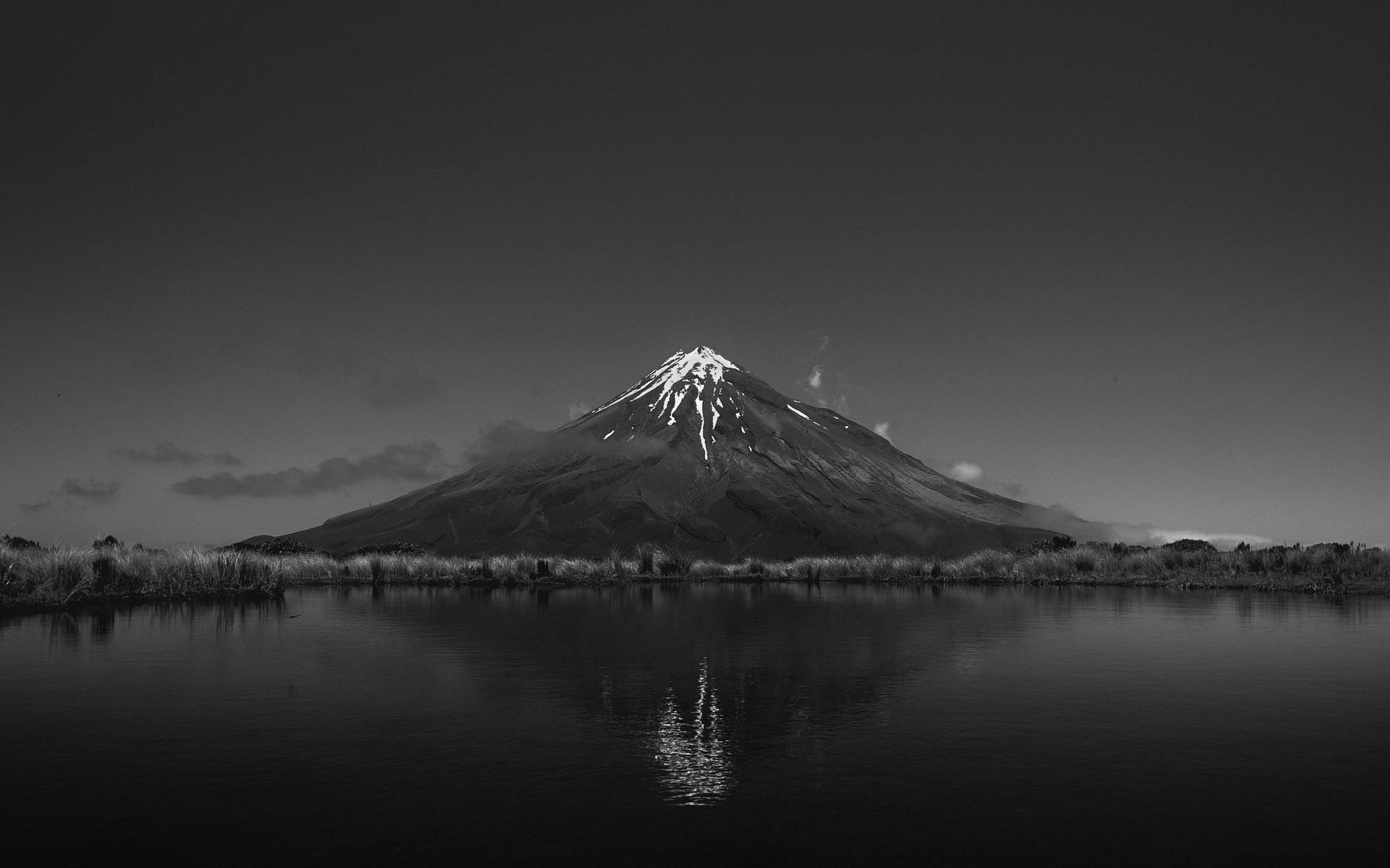 雪山峰在陰天倒映在靜止的水面上。