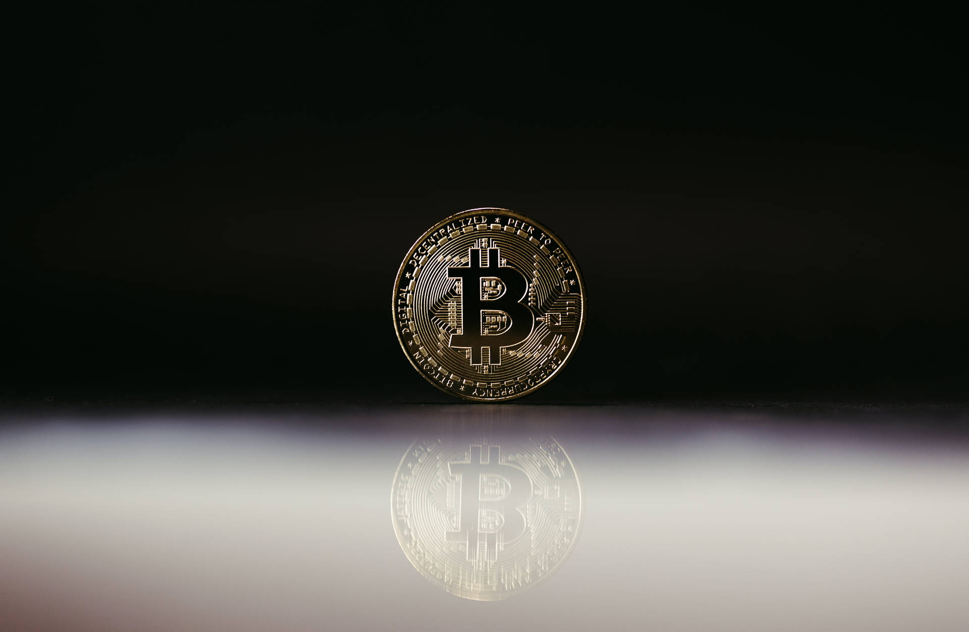在深色表面上反射的金色比特幣硬幣。