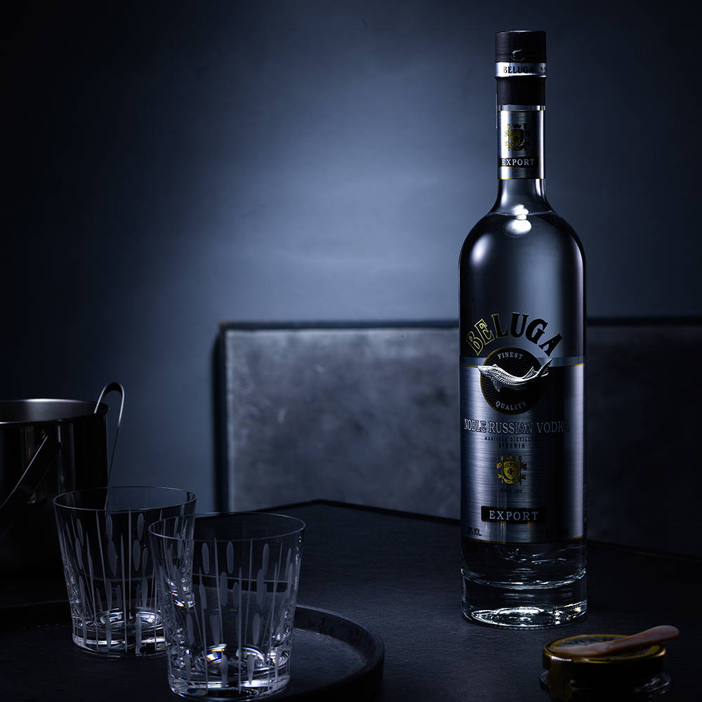 Beluga伏特加酒瓶與酒杯在深色吧檯上。