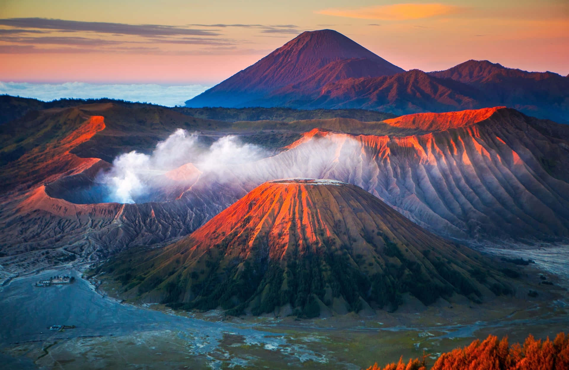 日出時噴出蒸氣的火山口，山脈在溫暖的光線中