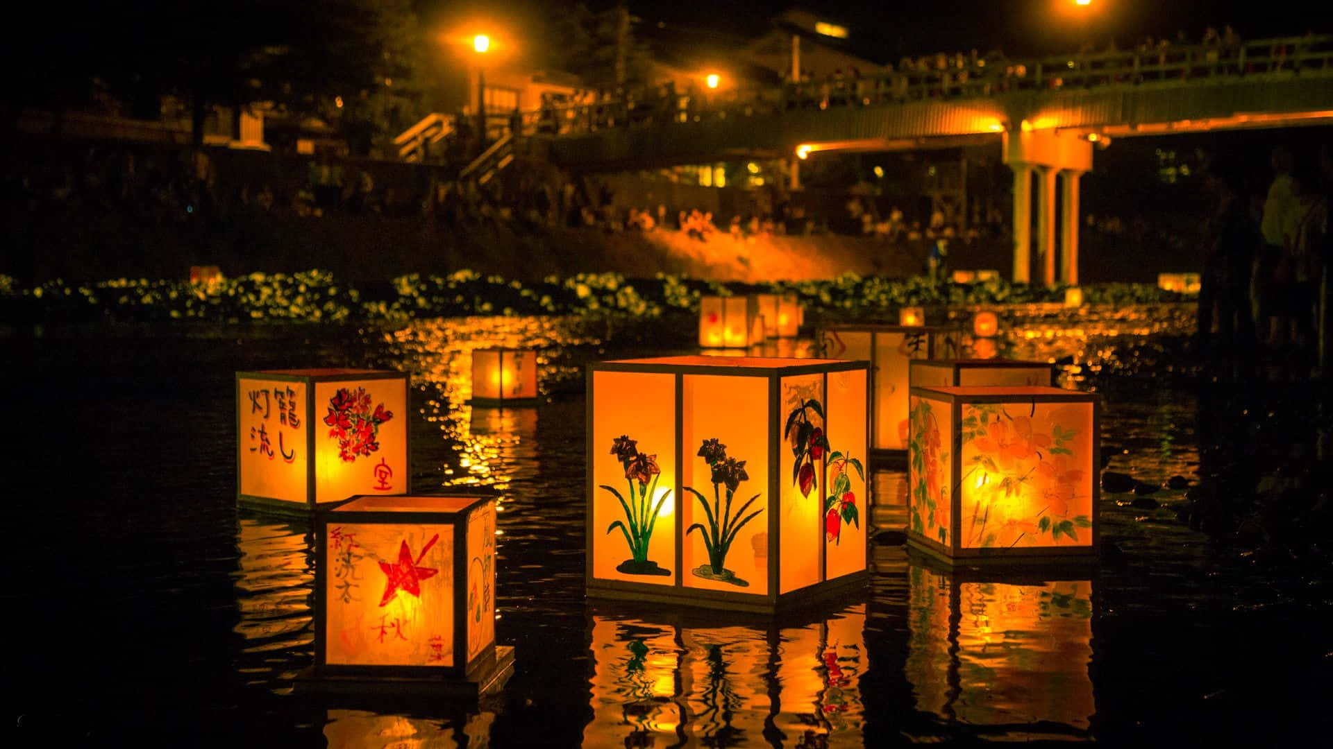 帶有花卉圖案的漂浮燈籠在夜間照亮橋下的河流。