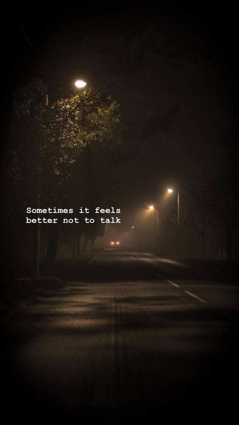 黑暗道路視角語錄 壁紙 — 一條霧氣瀰漫的夜晚街道，被遠處的路燈照亮，一輛孤獨的汽車車頭燈正在靠近。