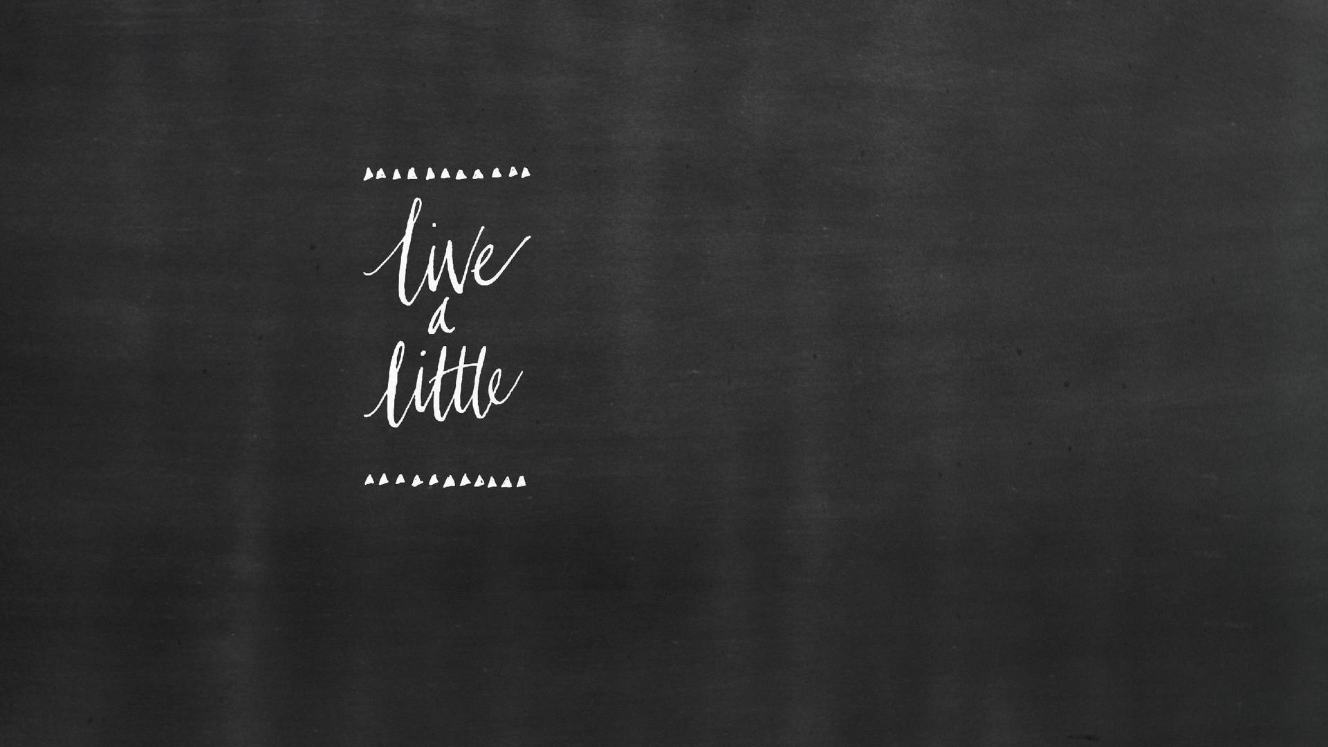 黑板上有白色手寫語錄「live a little」。