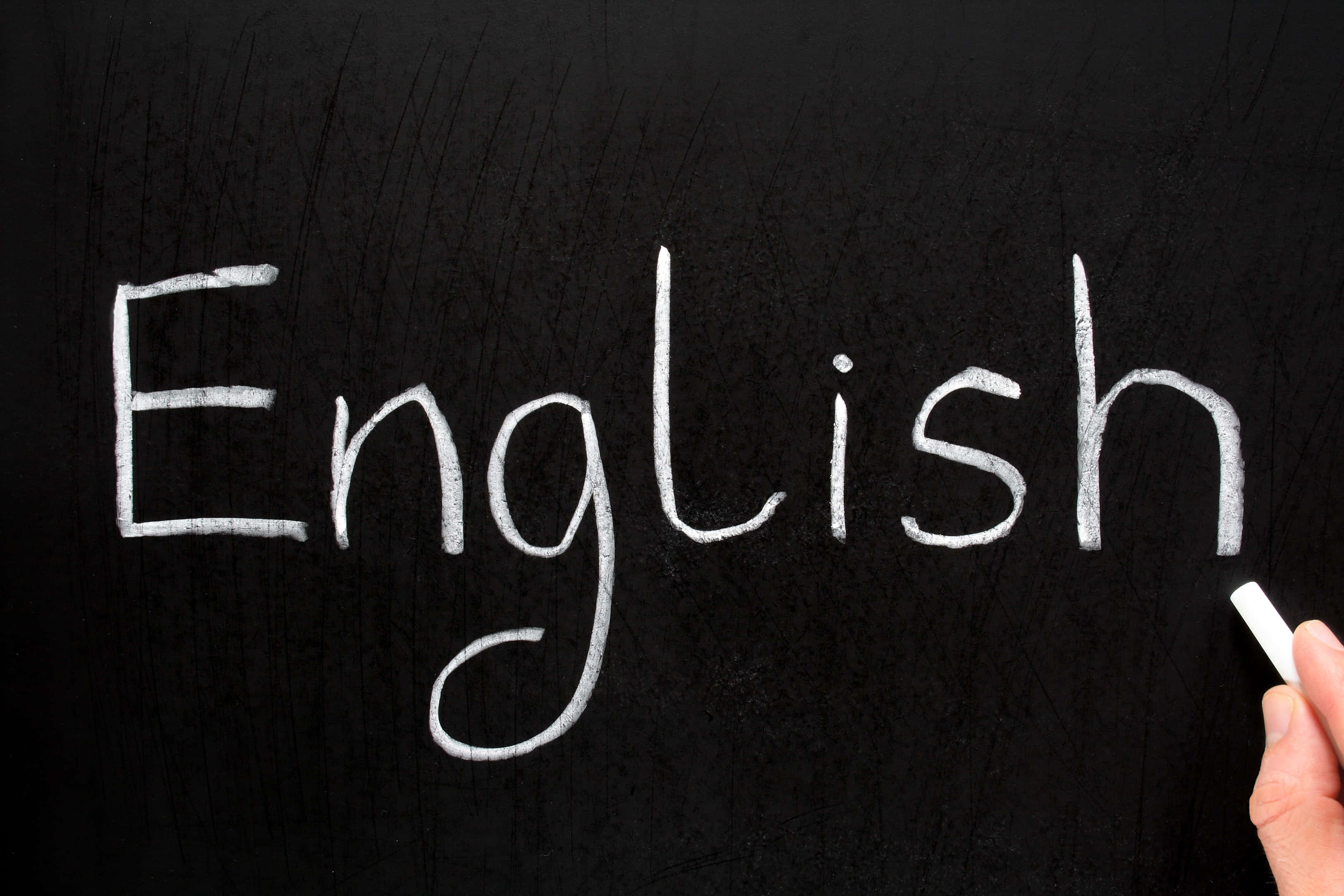 黑板上用粉筆寫著「英語」的攝影藝術圖畫 壁紙 — 手用白色粉筆在紋理黑板寫上英文一詞，右下角有一隻手拿著粉筆。